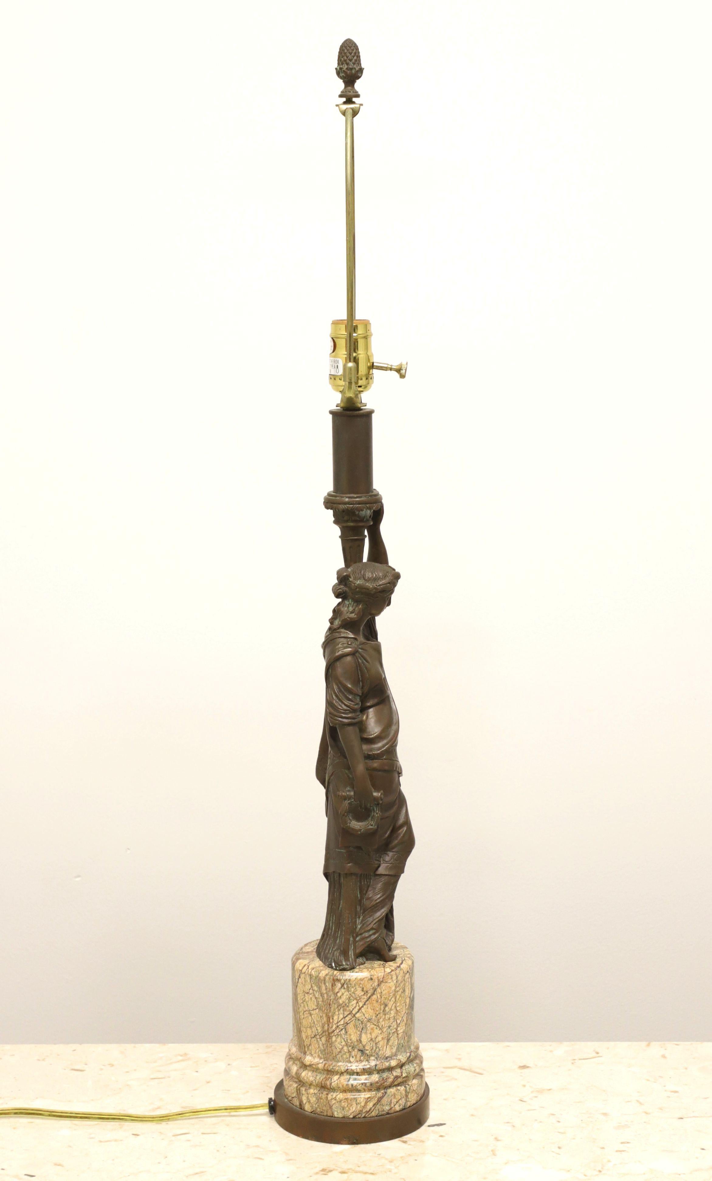 A Romanesque style statue formed as a table lamp, unbranded. Bronze statue of a woman holding a candle urn set onto a marble & bronze base. Single standard bulb socket with 3-way knob switch, brass harp and bronze pineapple finial. Likely made in