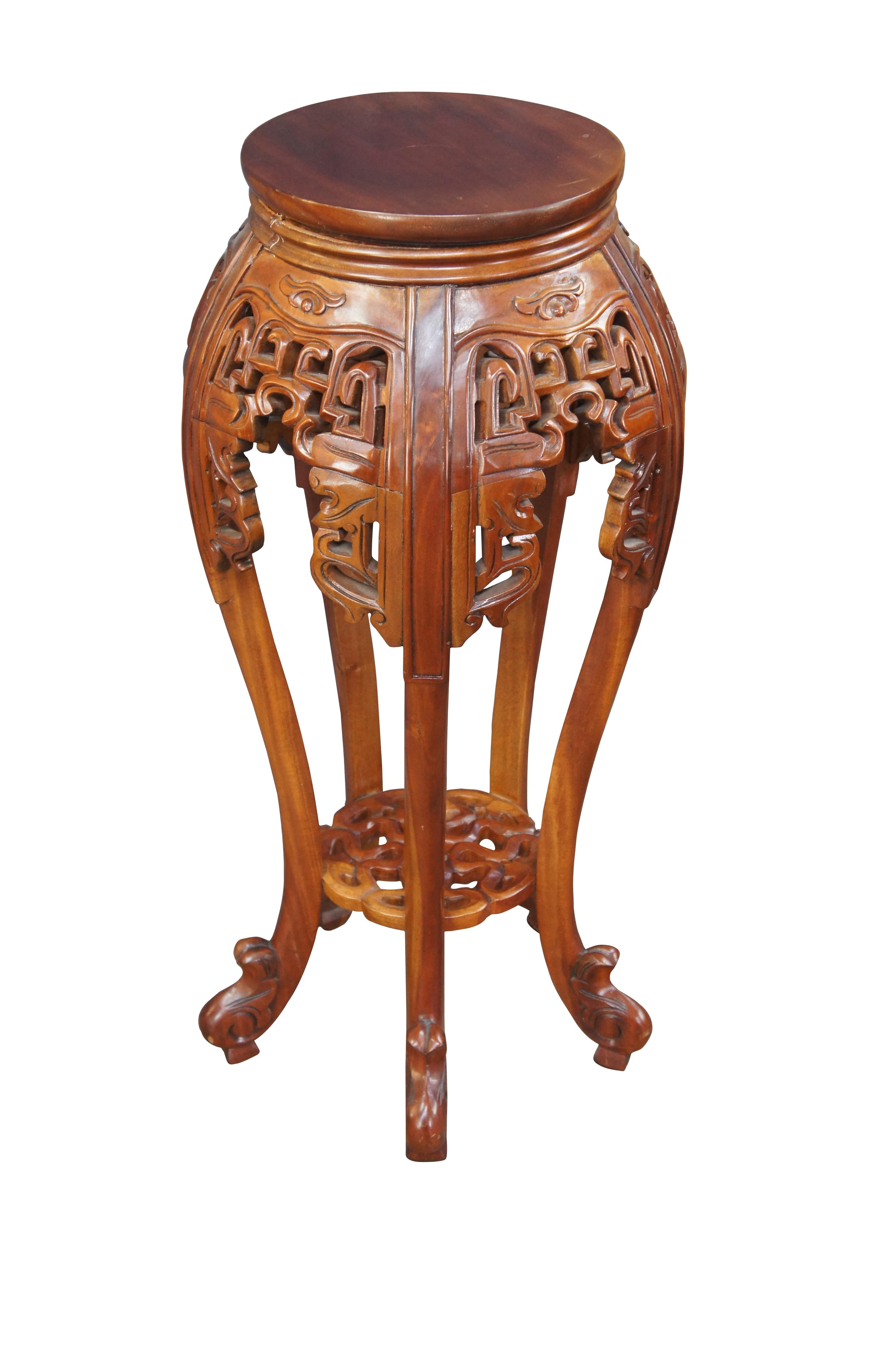 Mahogany carved Chinoiserie fern stand, circa last quarter 20th century. Features a solid wood construction with long contoured legs, pierced fretwork, a lower geometric shelf and scrolled feet.

Dimensions:
15.5