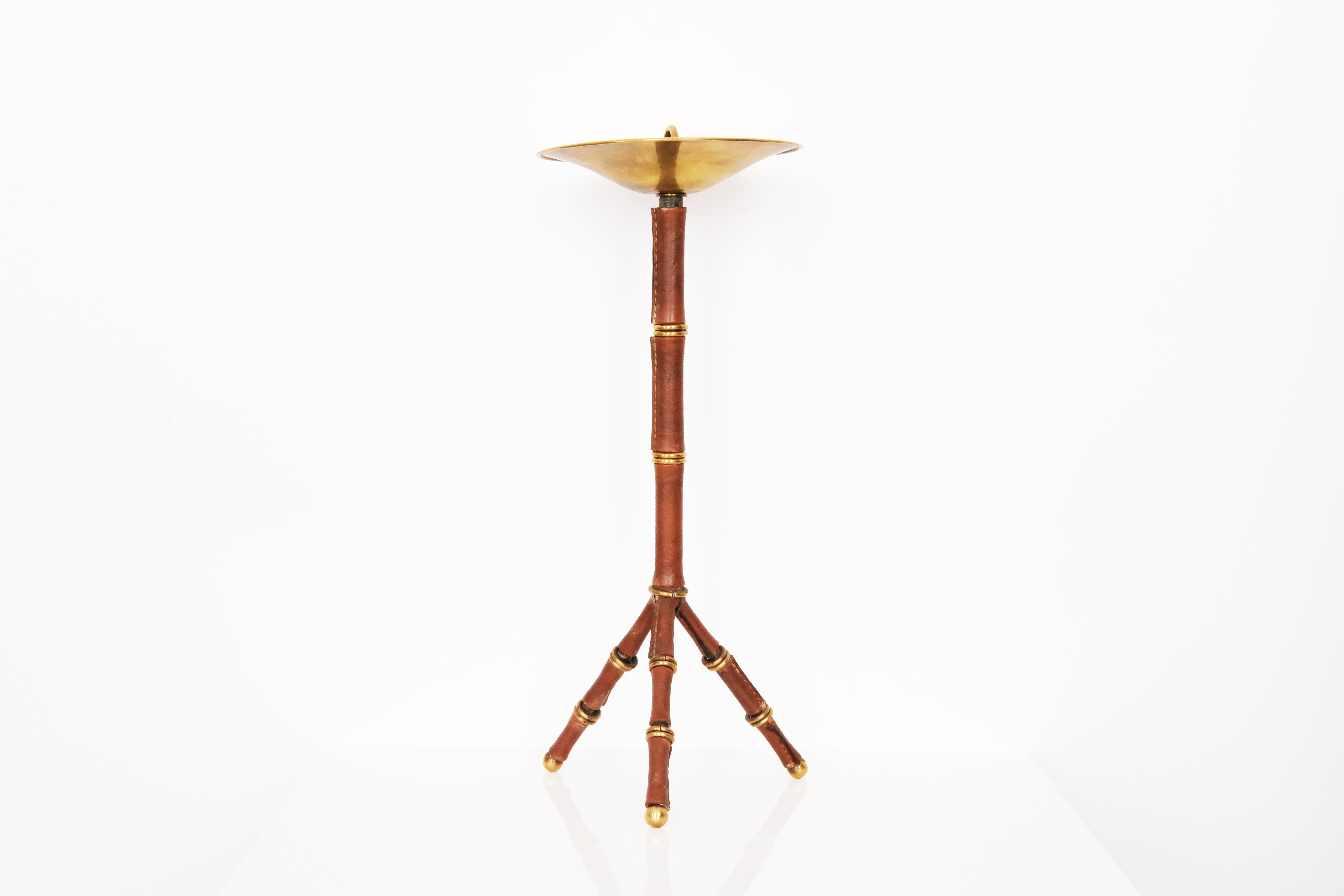 This striking piece is a Jacques Adnet smoking table, a refined example of mid-20th-century French craftsmanship. The table is crafted from rich leather-covered, saddle-stitched tripod base and a copper and metal ashtray, showcasing the designer’s
