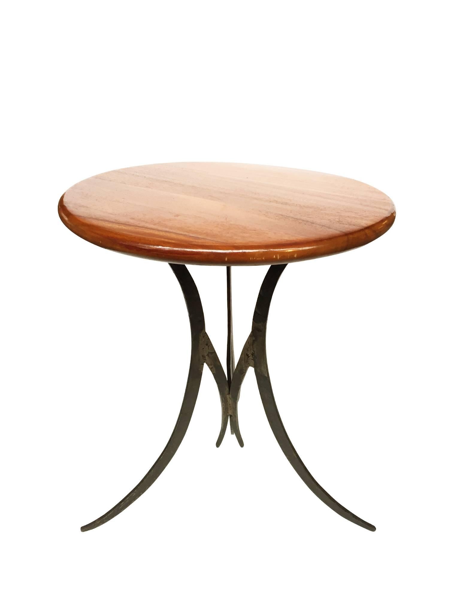 This unique vintage side or end table is comprised of a round, lacquered teak top and a Brutalist-style iron base. The fine wood striations of the teak add an ornamental element to the design, while the base is a mix of smooth edges and bold, curved