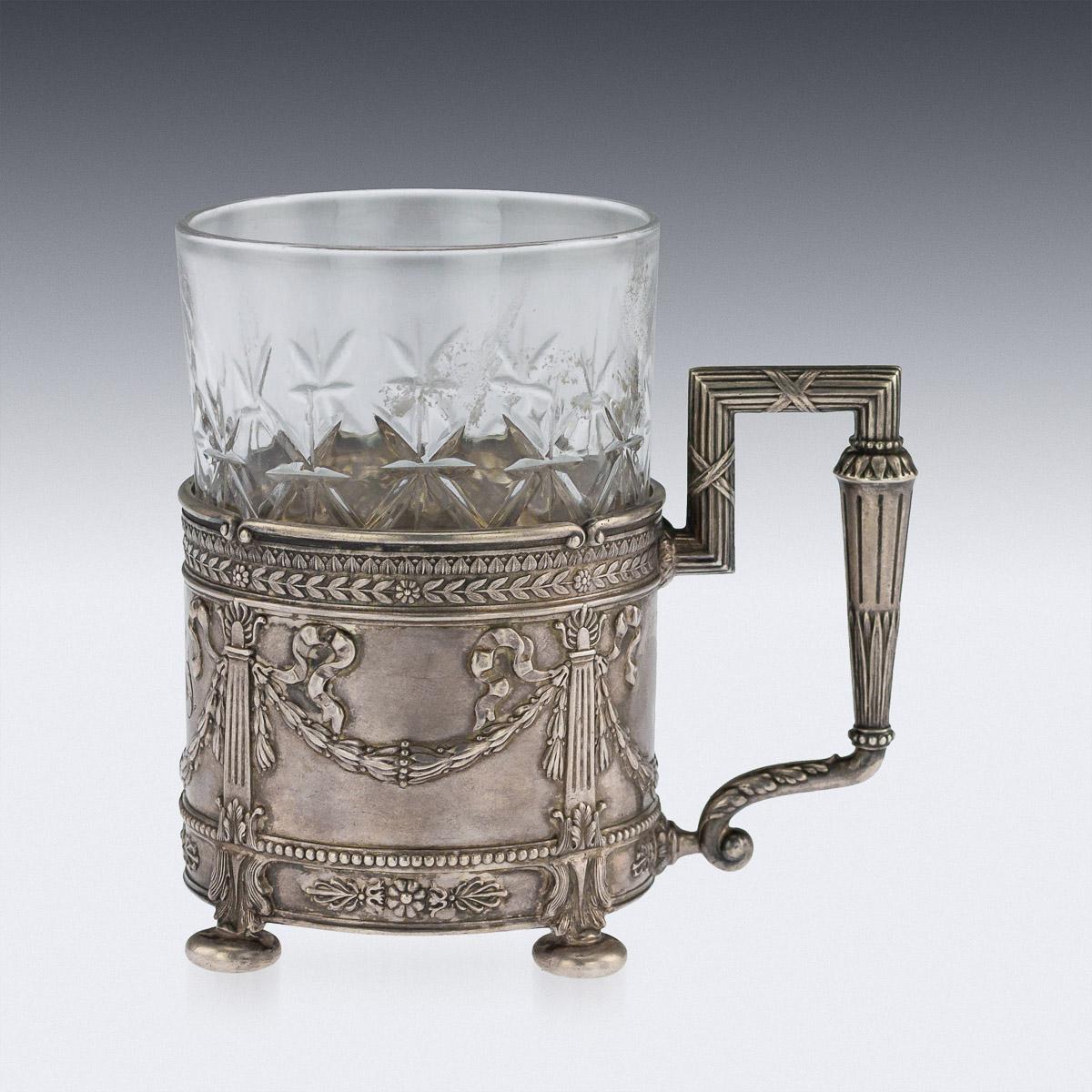Antique early 20th century Russian Empire style solid silver and cut glass tea holder, of straight cylindrical form, the glass cut with star facets, silver decorated with intertwining ribbon tied columns and laurel leaf swags, laurel boarders with