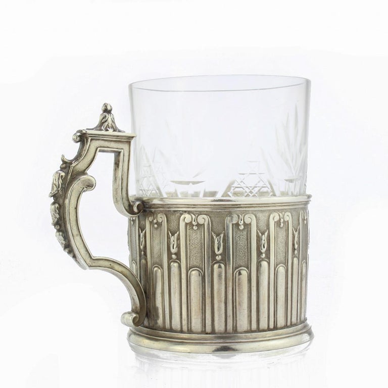 Antique early-20th century Russian Faberge solid silver tea glass holder, made in Imperial style, with fluted and floral decoration, applied with a scroll and leaf capped handle, and fitted with cut glass cup. Hallmarked silver 84 (875 standard),