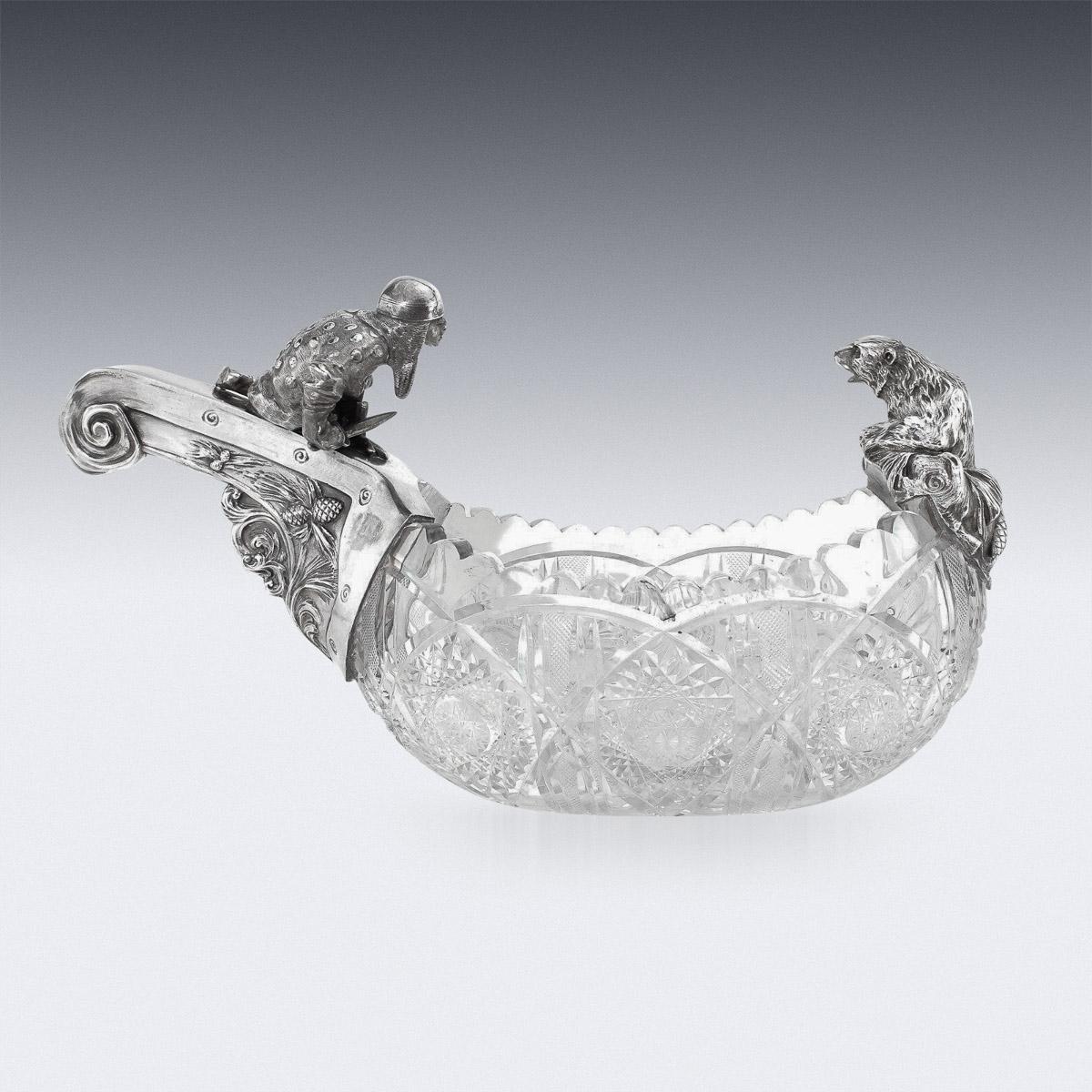 20th century Russian Pan-Slavic style silver & cut-glass kovsh, with a large curling mounted handle.The oval bowl with shaped rim, cut with diamond facets, the handle mounted with a finely cast bogatyr preparing to fight a bear that is climbing the
