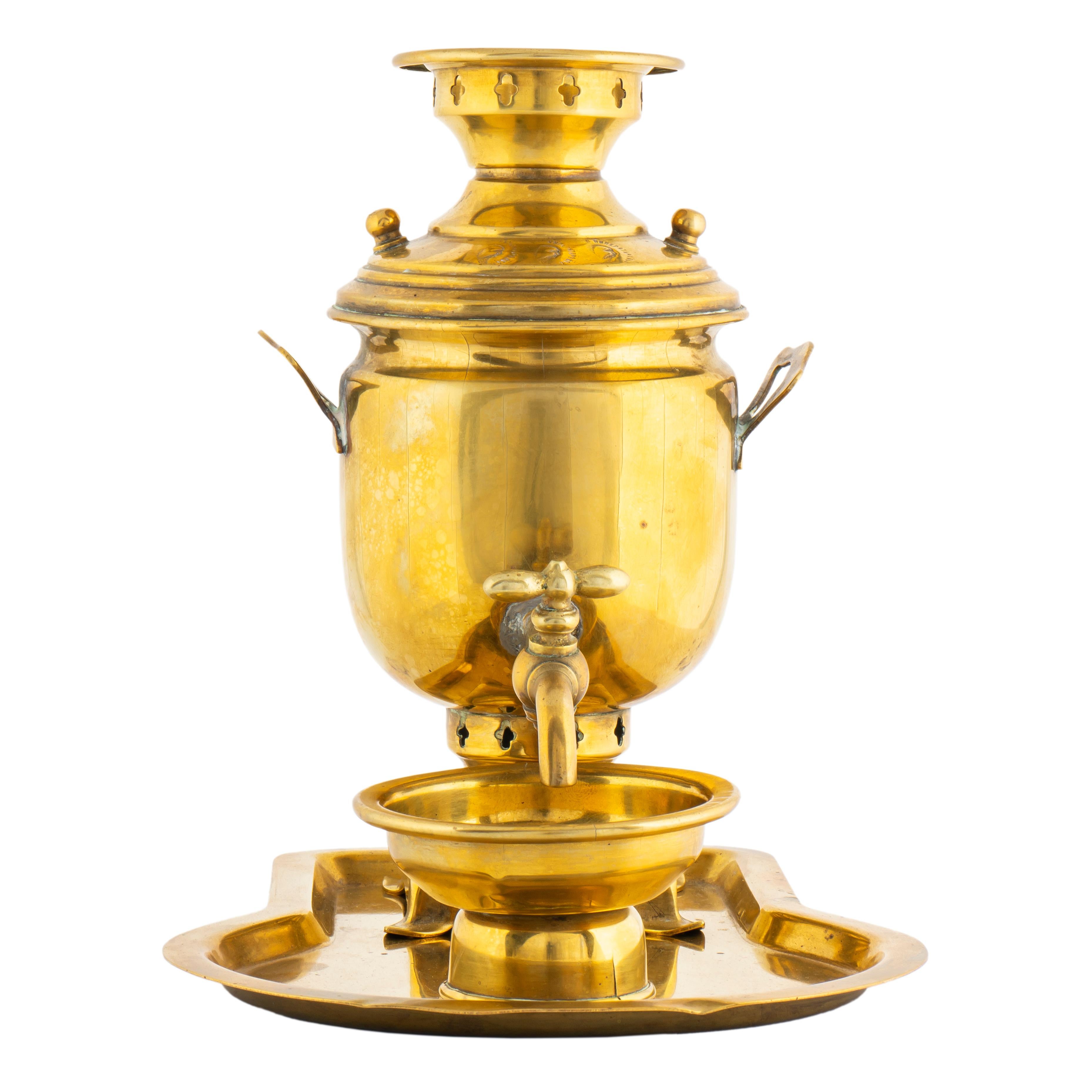 Of typical form in the Russian imperial style, a classic samovar set tooled in brass comprising a miniature brass samovar, drip bowl and tray. The samovar cylindrical with flared handles on a pedestal base, the front of lid stamped with three