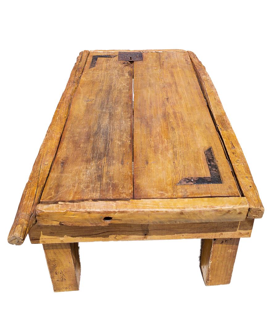 Rustic solid wood coffee table or cocktail table with eclectic hardware. This could be blended into a variety of home design styles. This is a repurposed wooden door that has been converted into a table with thick squared legs. The most interesting