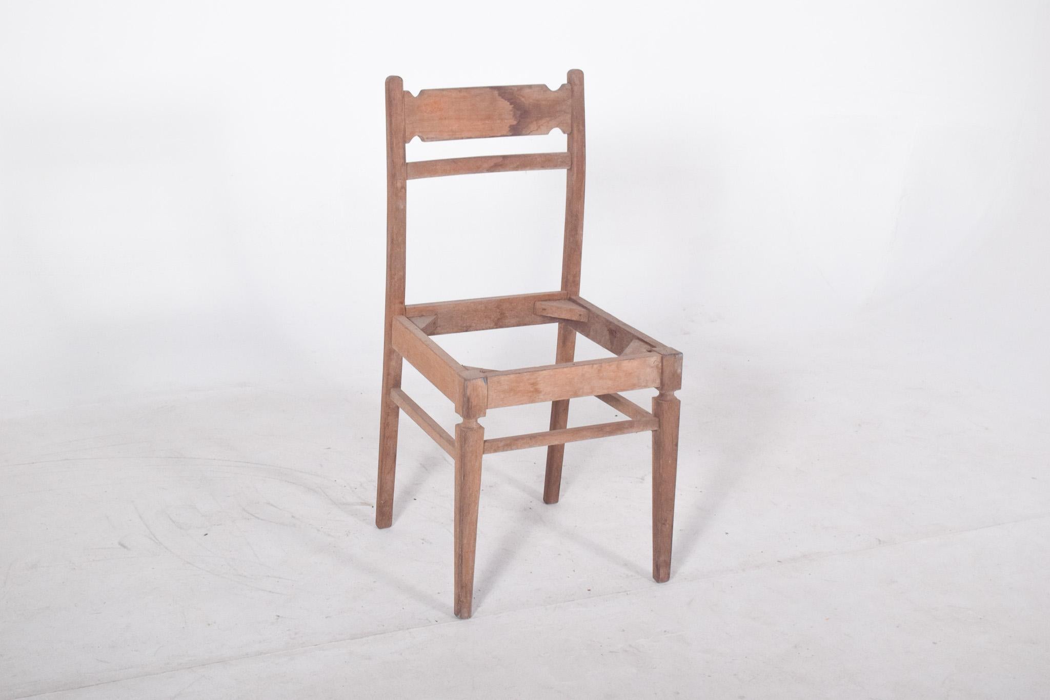 Silla de comedor rústica. Líneas sencillas, con un respaldo recto formado por dos travesaños horizontales, el superior ligeramente moldeado en los bordes, formando pequeños recortes geométricos. Las patas traseras están ligeramente inclinadas hacia