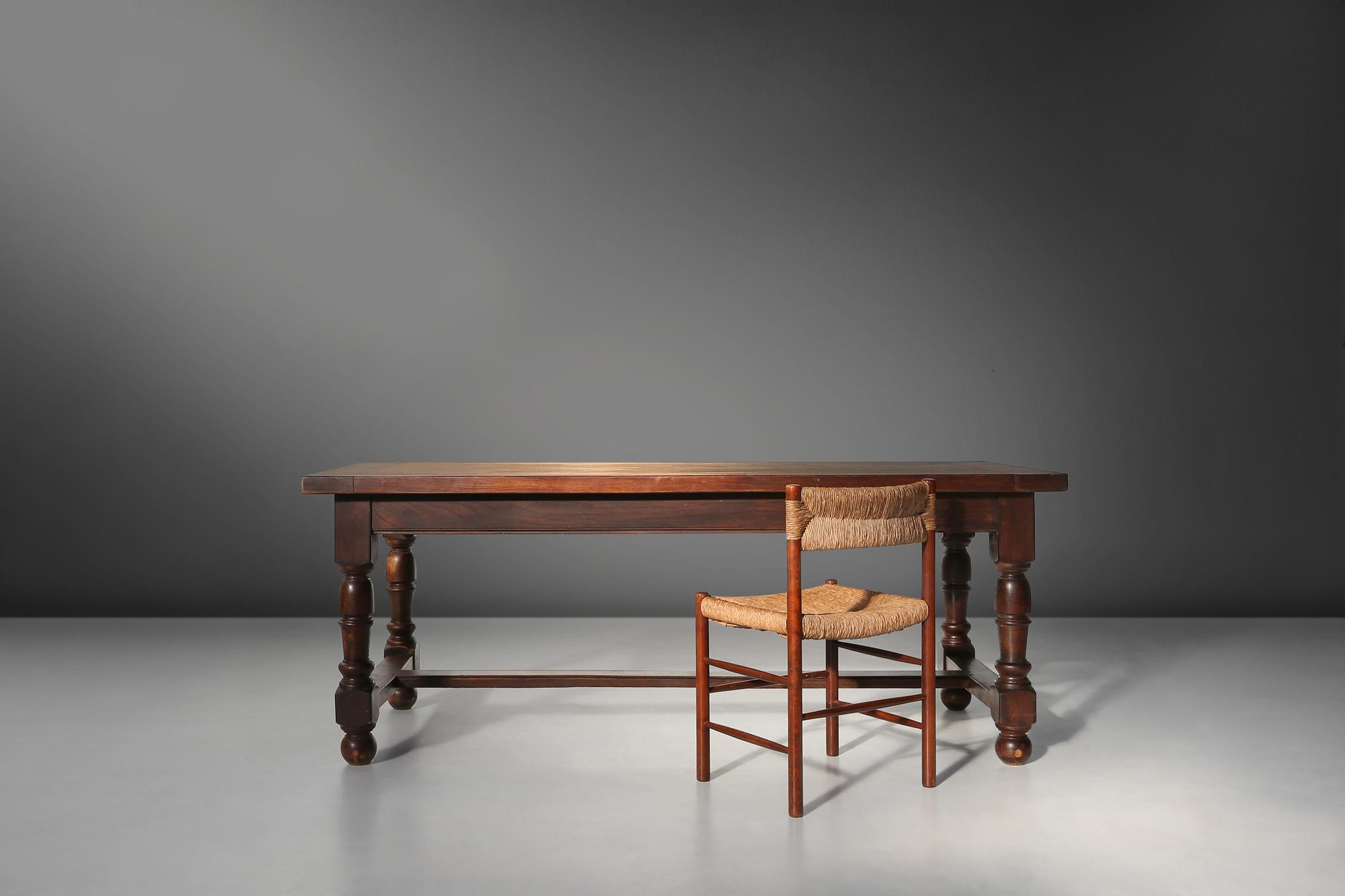 This 20th century rustic dining table is made of solid oak and has two drawers on each side, where you can store your cutlery, napkins or other items.

The table has round twisted legs and a crossbar connecting them, creating a sturdy and elegant