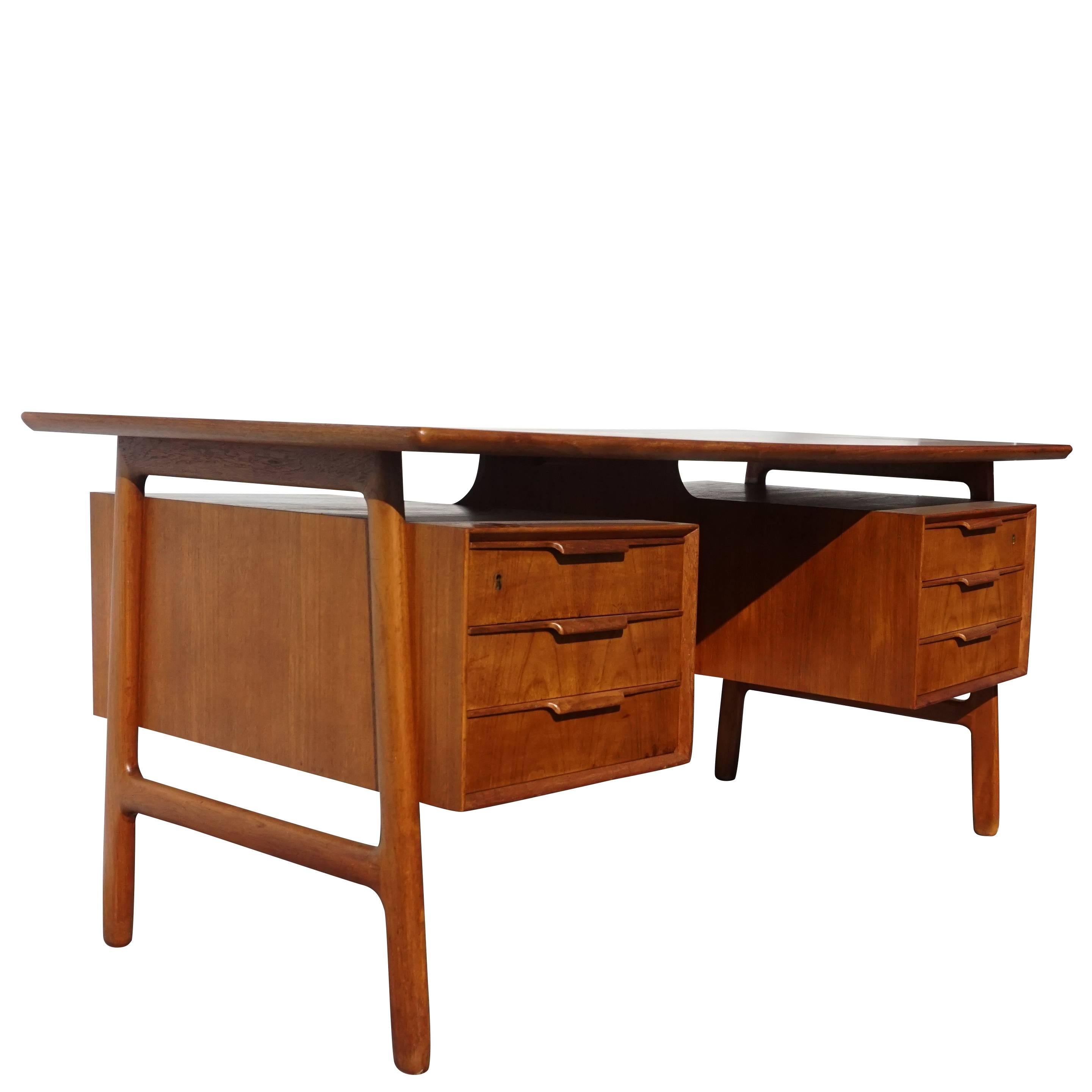 A vintage Mid-Century Modern Danish writing table designed by Bjarne & Gunni Omann, in good condition. The Scandinavian desk is made of hand carved cherry and beechwood, composed with six drawers, standing on four slightly curved wooden legs. Wear