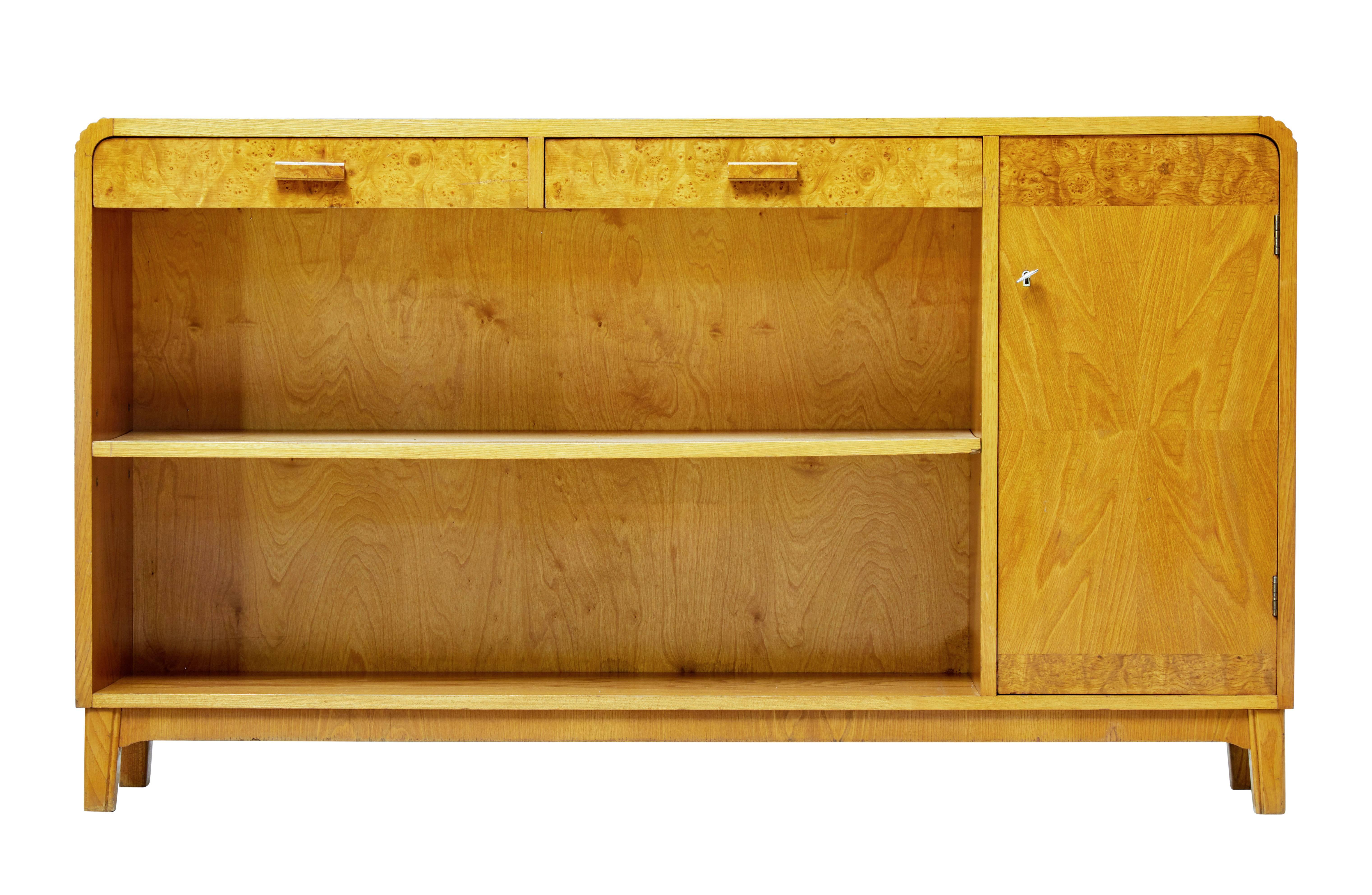 Good quality Swedish low open bookcase, circa 1950.

Very much in the Art Deco taste. Elm crossbanded with burr veneers. Single open shelf, with a single door cupboard containing a single shelf. Two drawers below the top surface. Grooved detail to