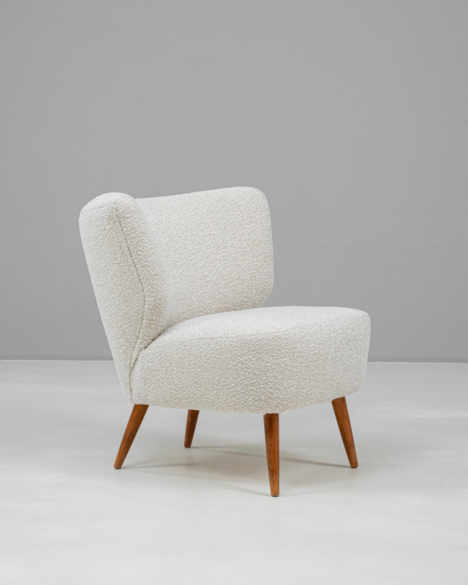 This elegant 20th-century Scandinavian chair showcases the essence of Nordic design with its sleek, understated silhouette and focus on comfort. Upholstered in a textured, neutral fabric, it exudes a soft, inviting charm. The chair features a curved