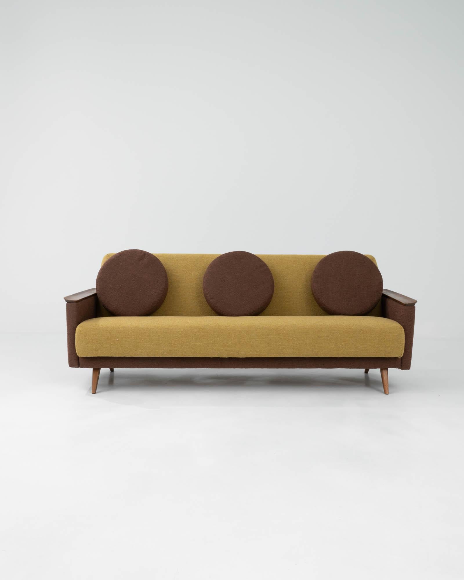 Made during the 20th century, this vintage sofa beautifully blends the whimsical mid-century modern aesthetic with the functional minimalism of Scandinavian furniture. Its design combines angular and circular elements, showcasing splayed tapered