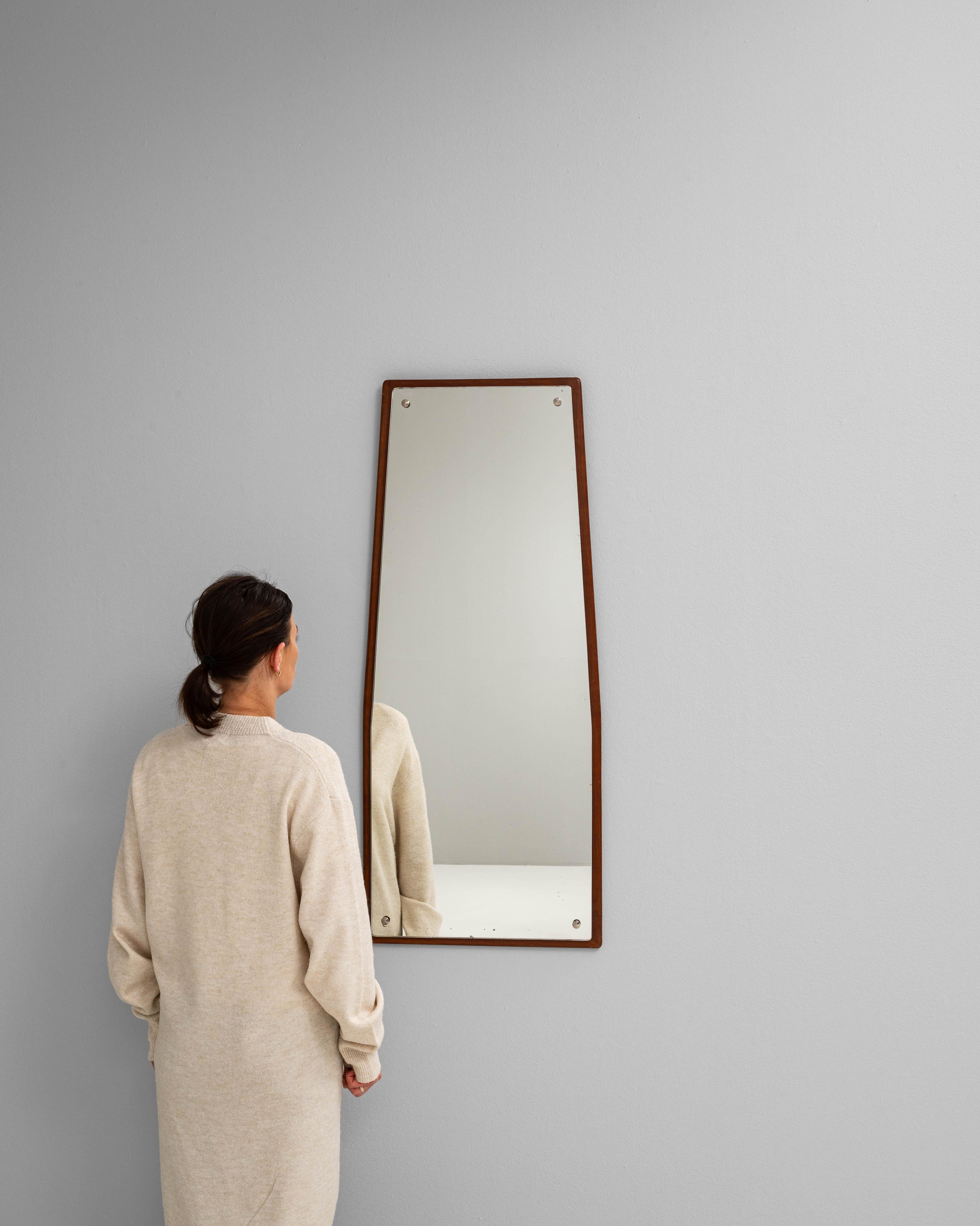 Ce miroir scandinave du XXe siècle présente un design épuré et minimaliste avec une silhouette trapézoïdale subtile, reflétant l'élégance fonctionnelle caractéristique du modernisme nordique. Le miroir biseauté est monté sur une plaque arrière en
