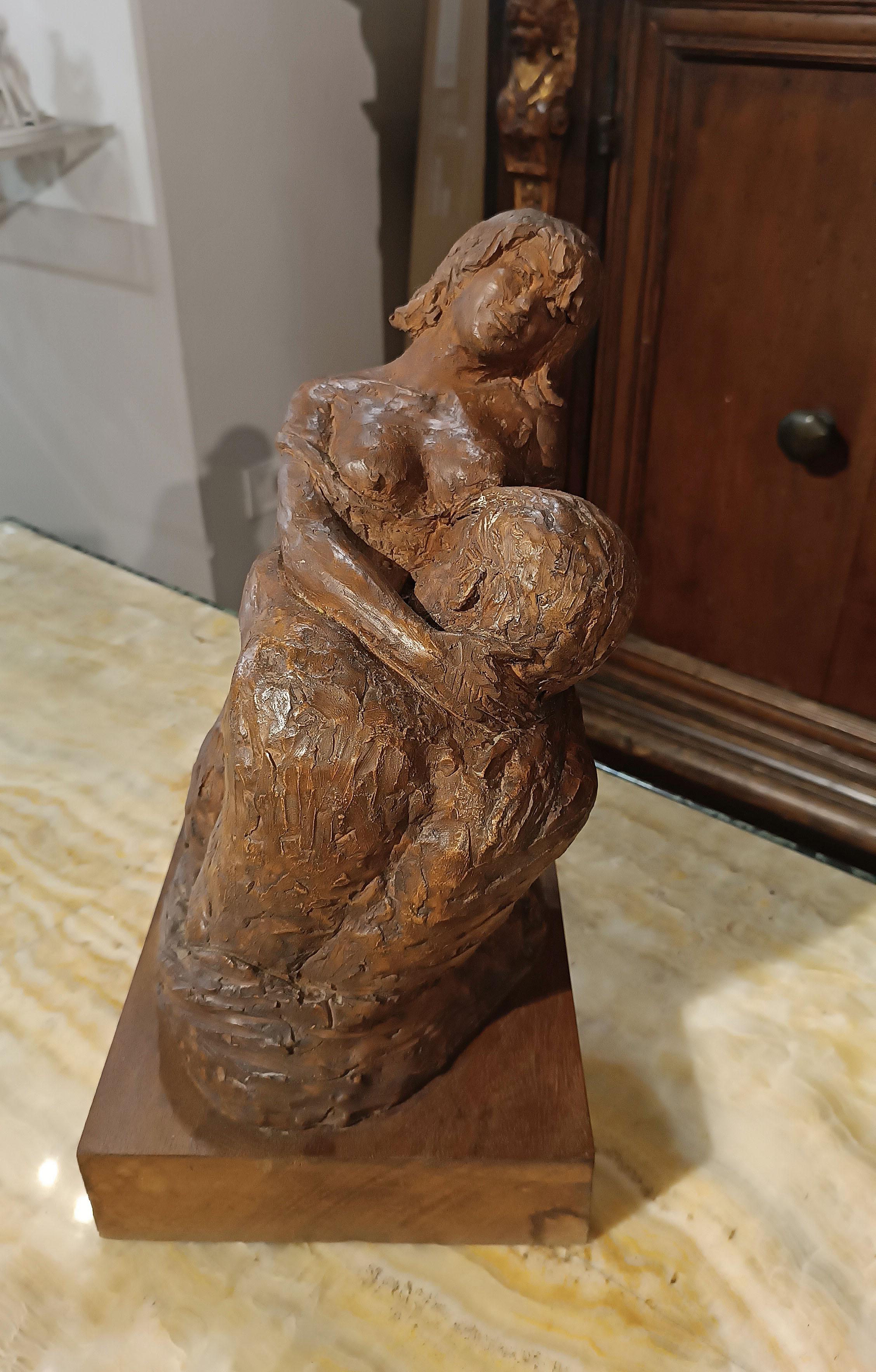 Enchanting terracotta sculpture depicting the embrace between two lovers. The woman, with her breasts exposed and on her knees, embraces and is embraced by the man in a passionate and romantic gesture. Both figures, half-length, convey intensity and