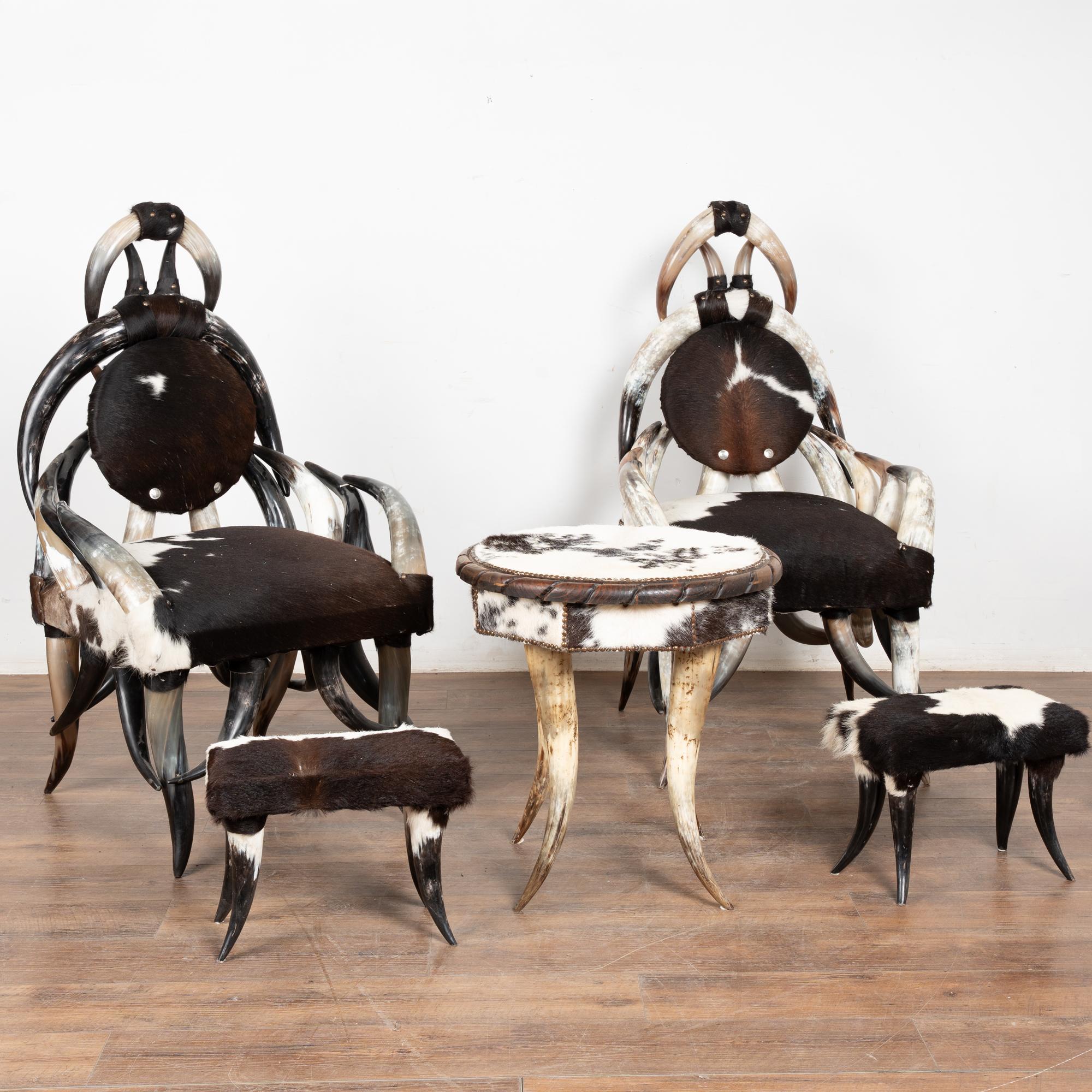Remarkable set (5) of horn and hairhide armchairs, ottomans and round side table. 
Bring a touch of the rugged West to your interior with these authentic steer horn and hair on hide armchairs (2), matching ottomans (2) and round accent table