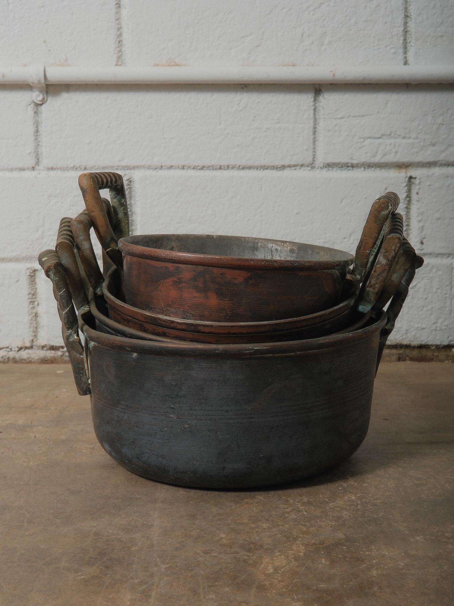 A beautifully aged collection of hand-crafted copper pots, each vessel showcasing a warm, time-worn patina and subtle hammer-worked surface. This set features rich tonal variations ranging from deep umber to soft rosy copper, with traces of