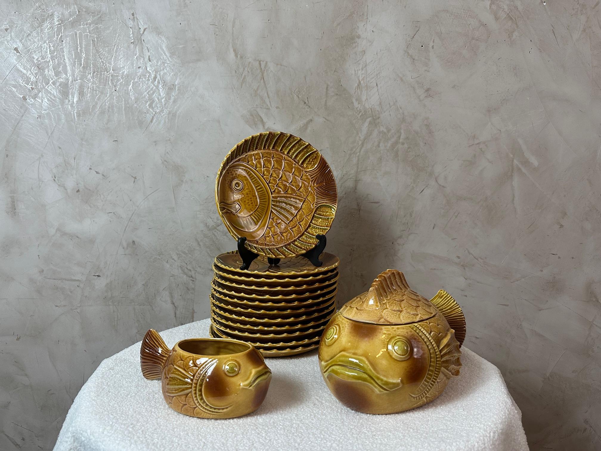 Beautiful vintage fish-themed dinnerware set in glazed ceramic, dating from the 1950s made by the French Manufacture Sarreguemines. 
This charming ensemble includes 12 plates decorated with a relief fish motif, along with a matching tureen and sauce