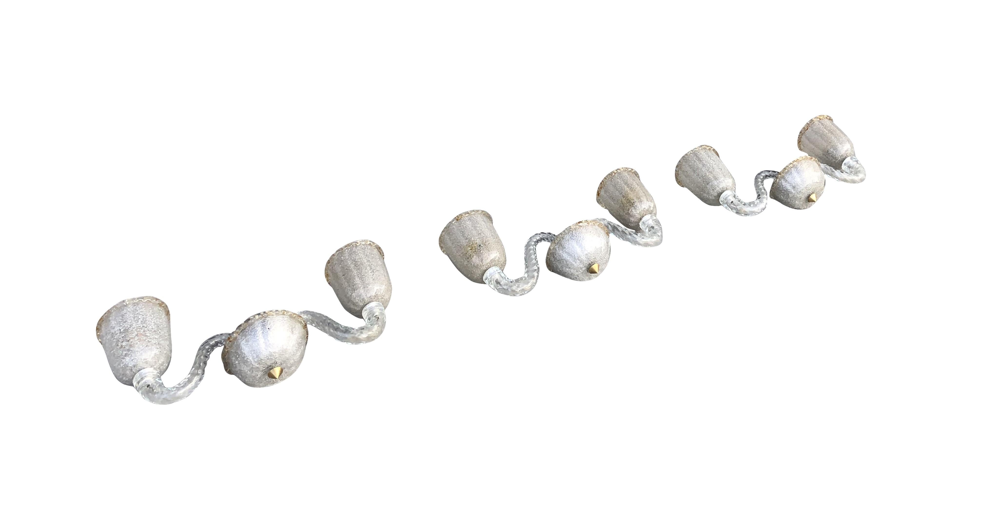 A vintage Mid-Century Modern Italian set of three wall sconces, appliques made of hand blown frosted, smoked stamped Murano glass. Each shade is featuring a one light socket, in good condition. The wires have been renewed. Wear consistent with age