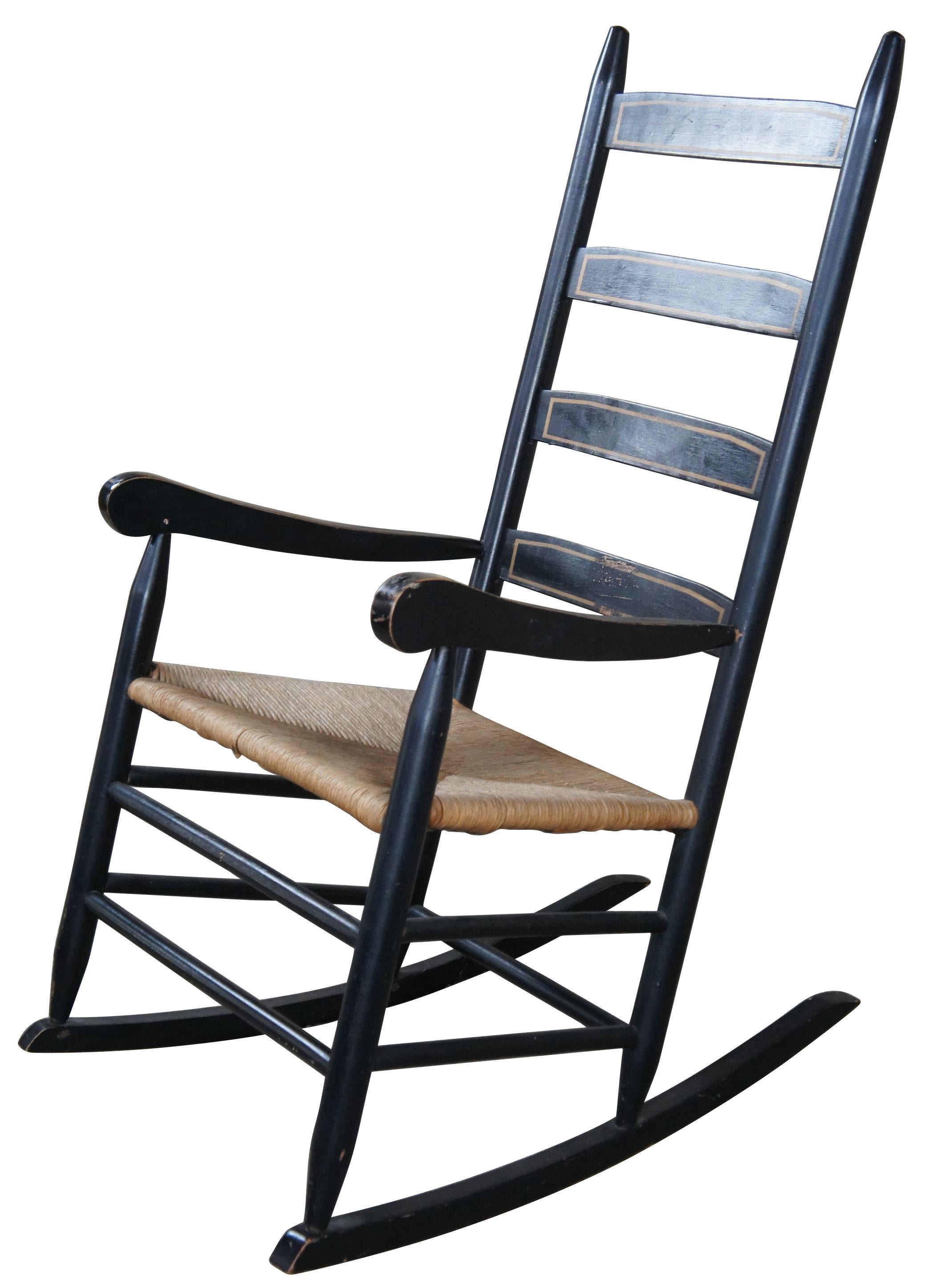 20th Century shaker style rocking chair. Features a black finish with gold trim along the back rails and a rush seat.