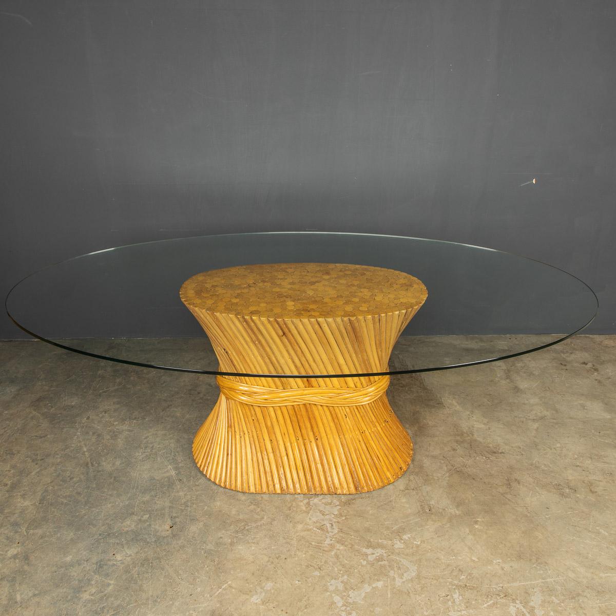 A large iconic wheat sheaf dining table with an oval glass top and bamboo pedestal by American designer McGuire, circa 1970. This piece will seat six comfortably.

CONDITION
In Good Condition - wear consistent with age, only minor wear and tear.