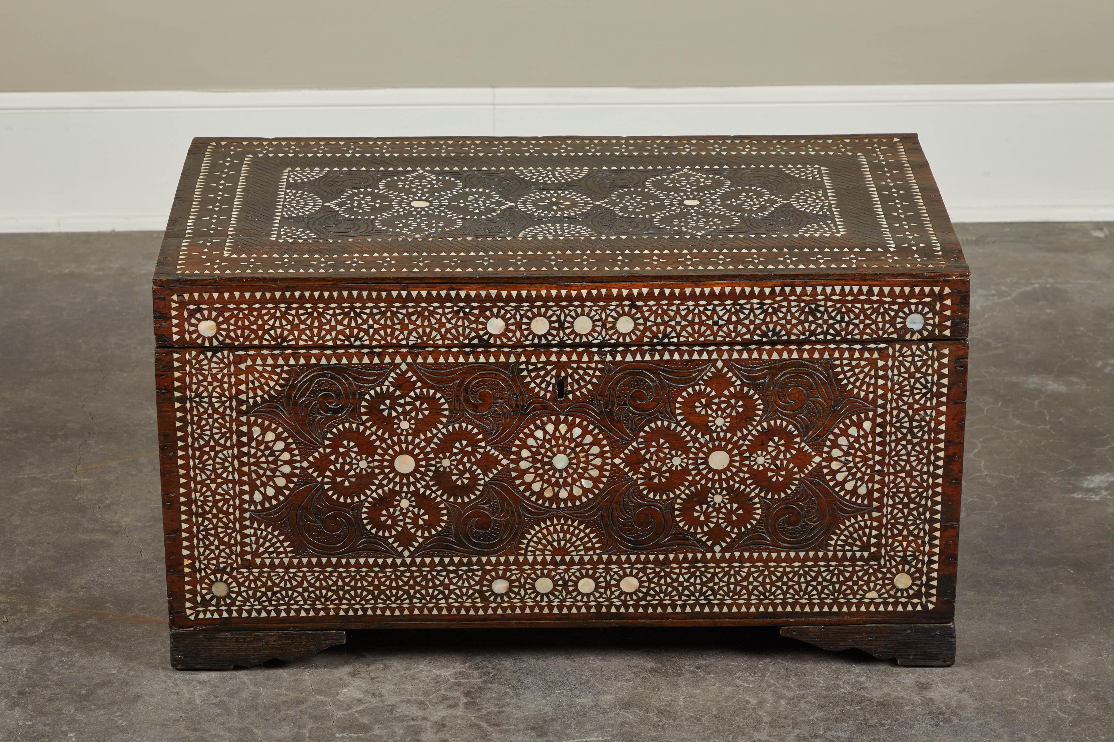 A dark-wood 20th century heavily-inlaid trunk of Filipino origin. Handles on either side and hinged top make it functional as occasional storage, as well.