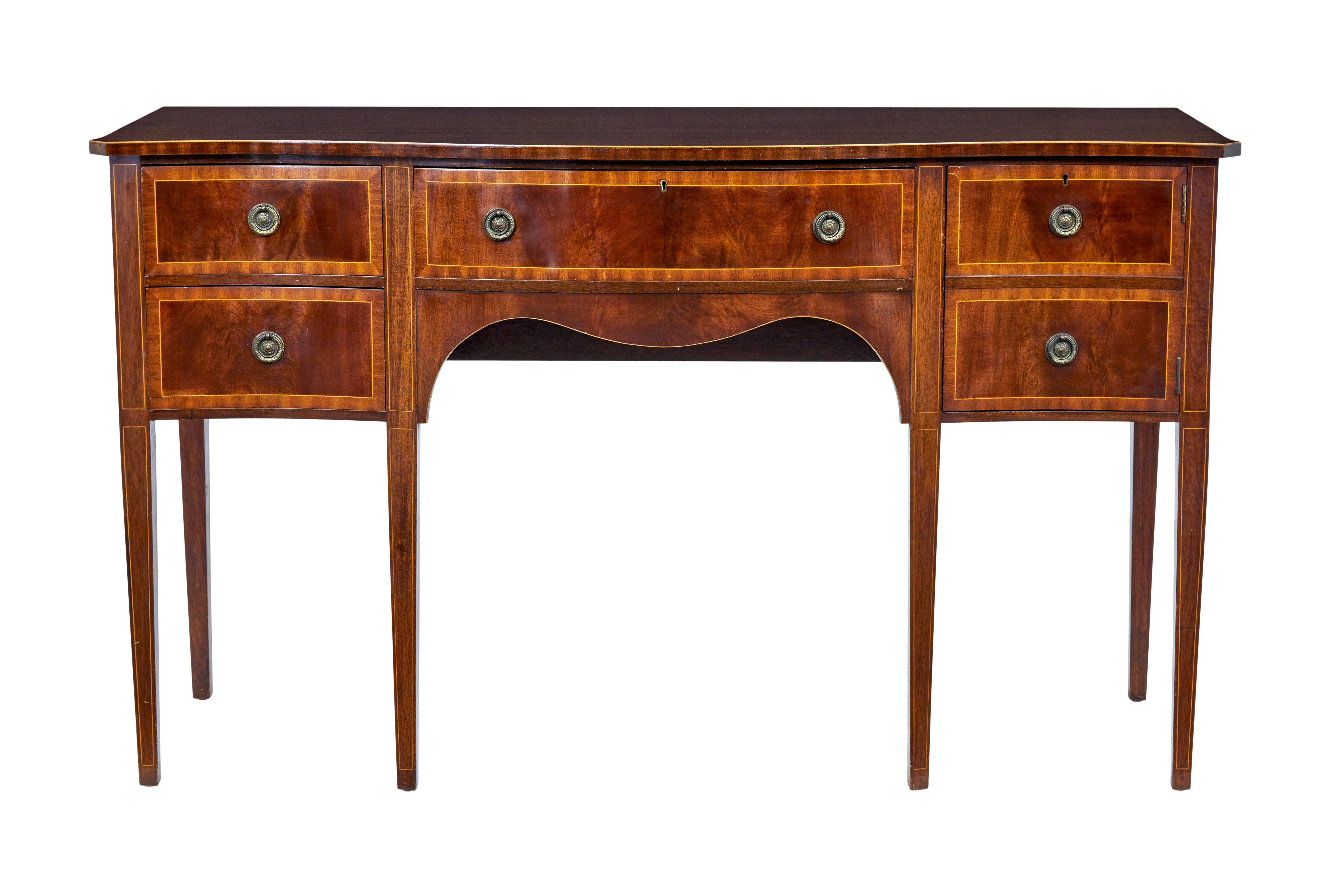 20th century Sheraton influenced mahogany sideboard circa 1970.

Good quality serpentine shaped sideboard/buffet made in the sheraton style.  Plain top surface with strung edge.  Central drawer flanked with 2 drawers to the left and a concealed