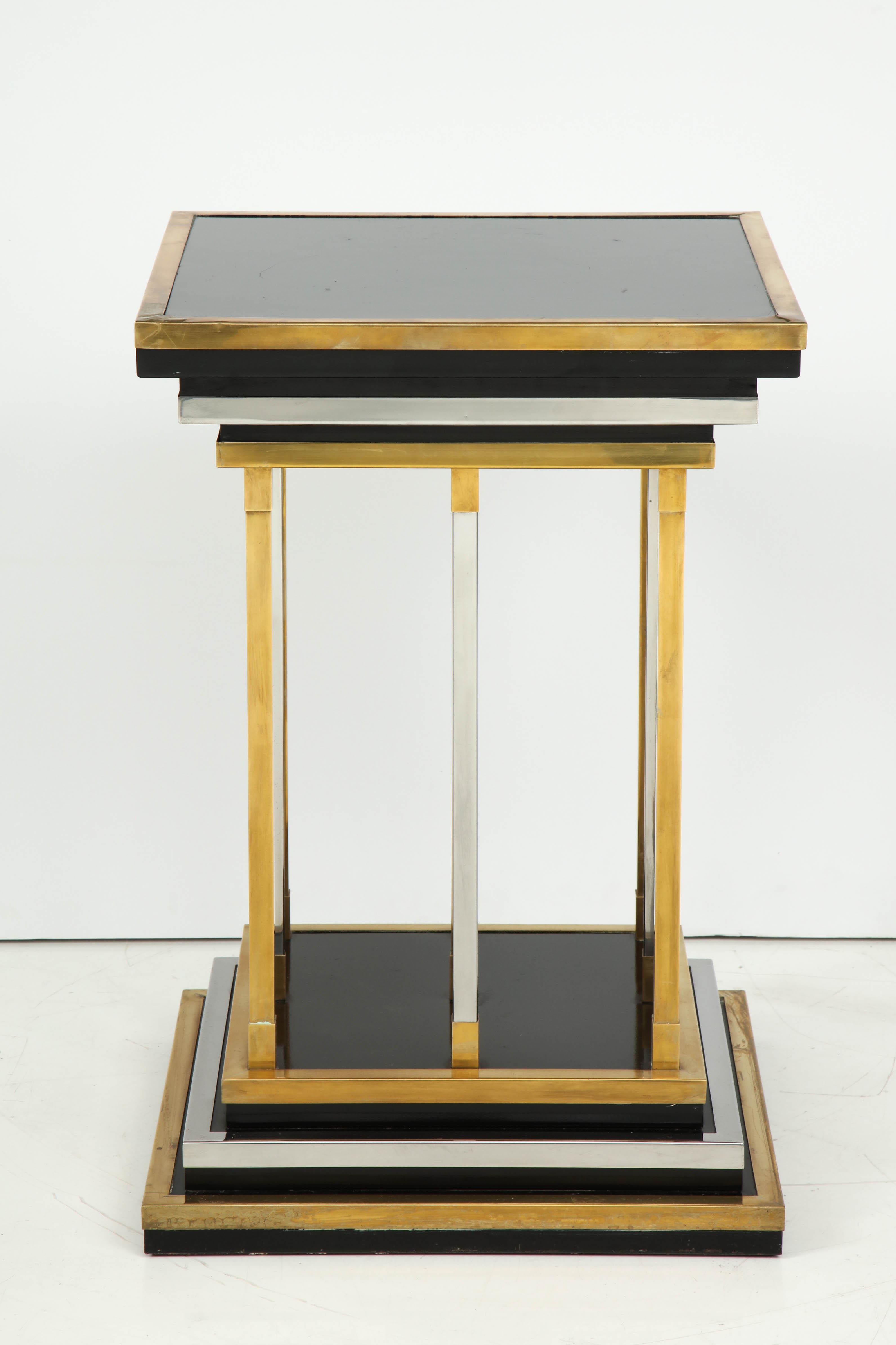 20th century polished brass and black lacquer side table, the top and base stepped and graduated, supported by nine brass bars.