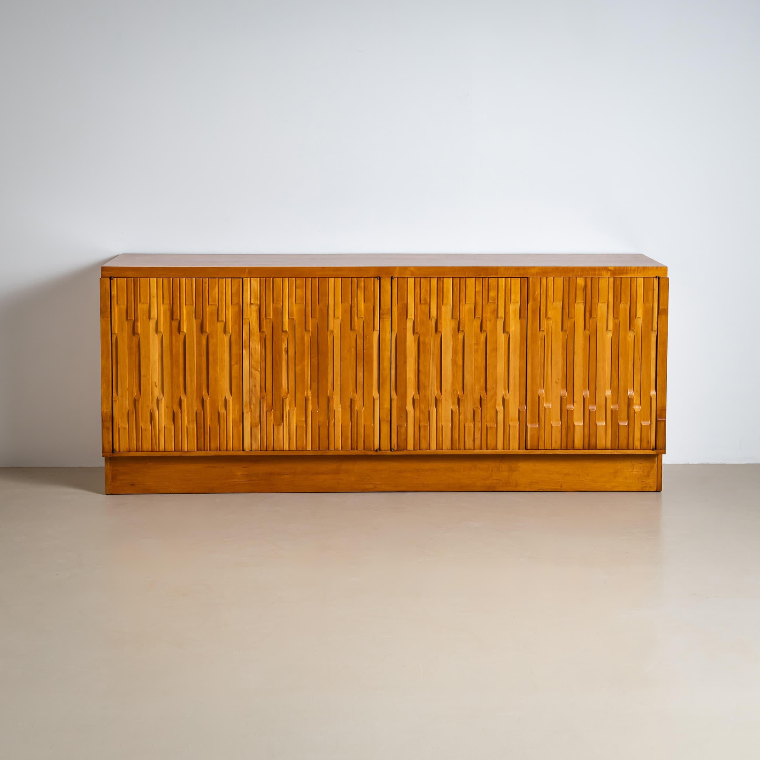 A four-door sideboard designed in the style of Luciano Frigerio in the 1970s, crafted from beechwood. The striking door design, featuring offset wooden slats, gives the piece a dynamic, sculptural appearance— a signature of Frigerio's design