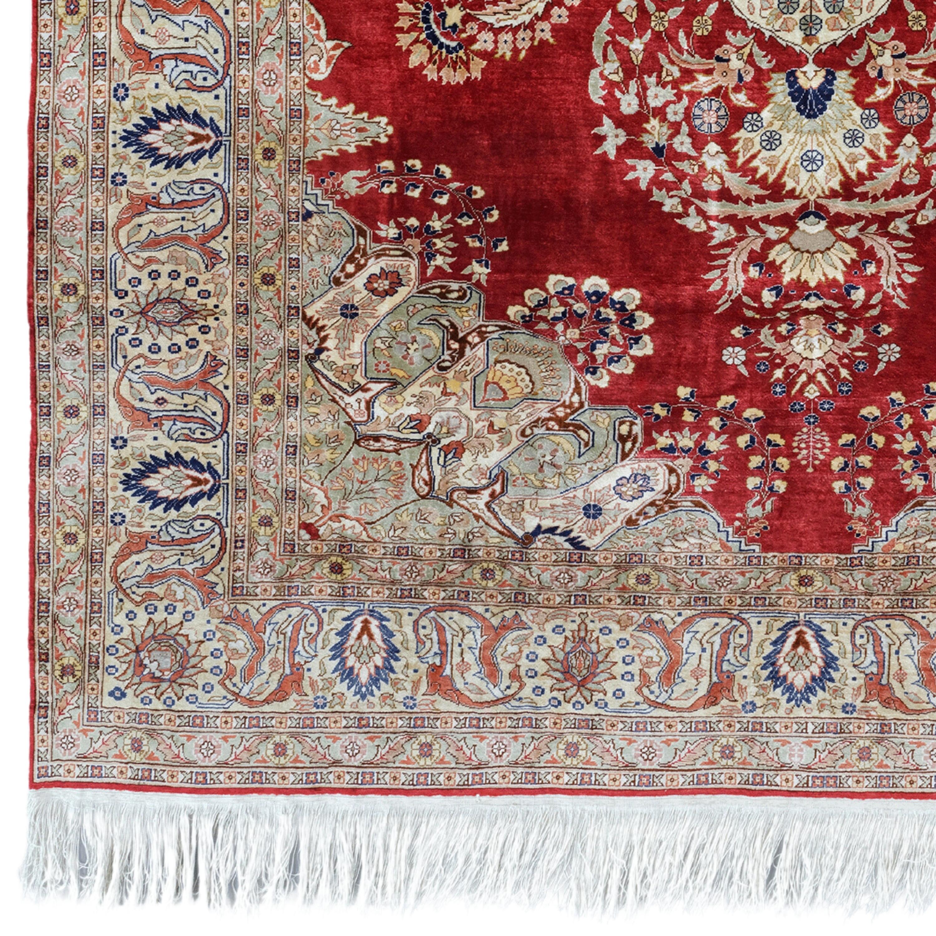 The Art of the Elegant Touch This antique silk Kayseri carpet from the early 20th century stands out with its intricate floral and geometric patterns embroidered on a rich and deep red background. Colors in shades of cream, blue and gold adorn the