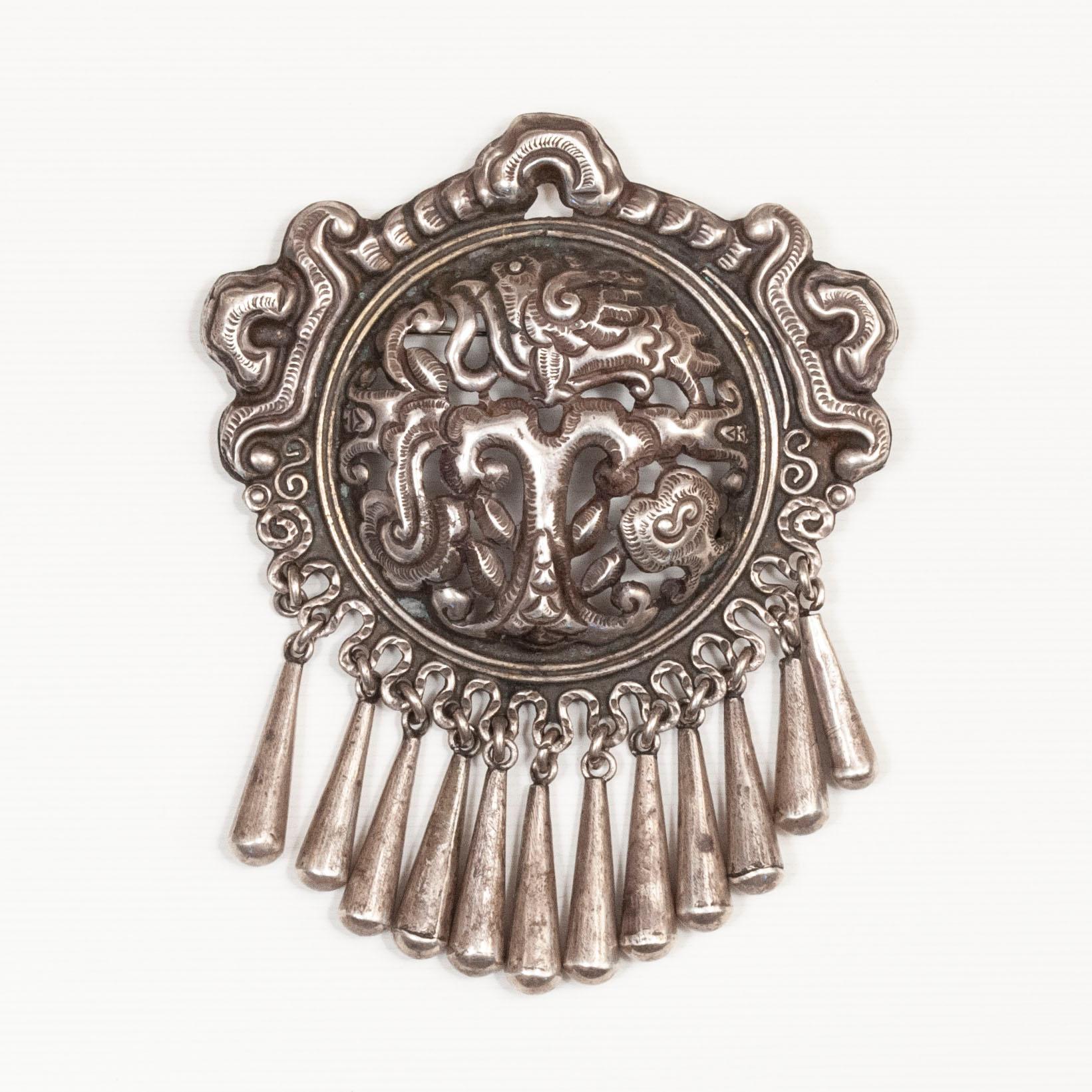 A large silver repoussé brooch designed by Matilde Poulat and made by Ricardo Salas, her nephew. Matilde Poulat was an influential jewelry designer who opened her Mexico City workshop in the 1930s.

The piece is composed of a central medallion