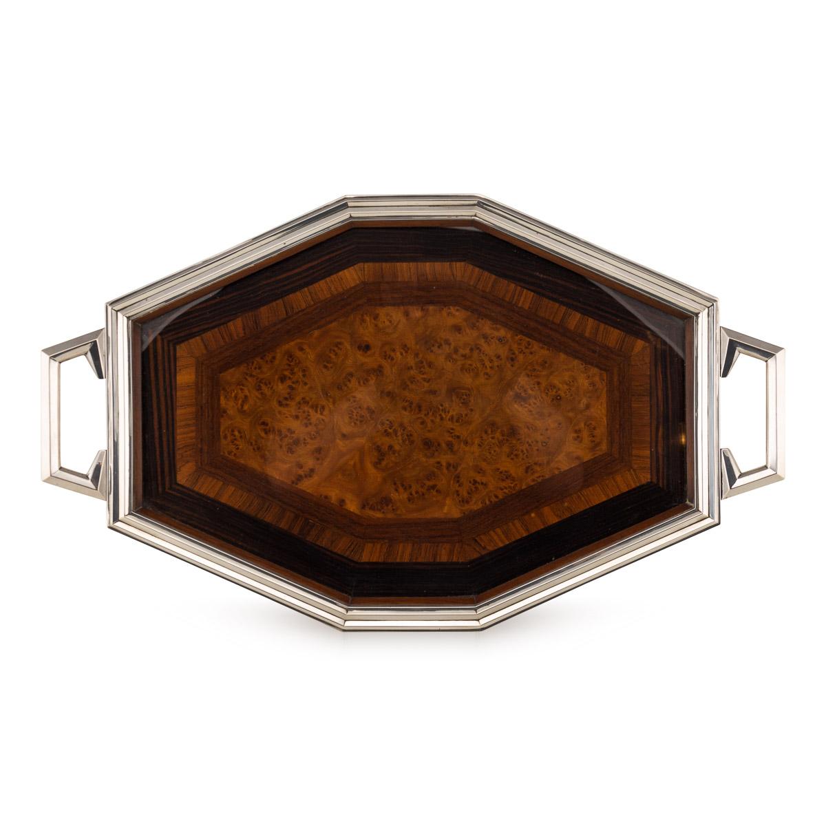 A stylish wooden tray with a continental silver frame and handles. This French tray is decorated with tulip wood burr walnut and ebony marquetry under glass. This would be perfect for any modern or mid century interior whether for home use or office