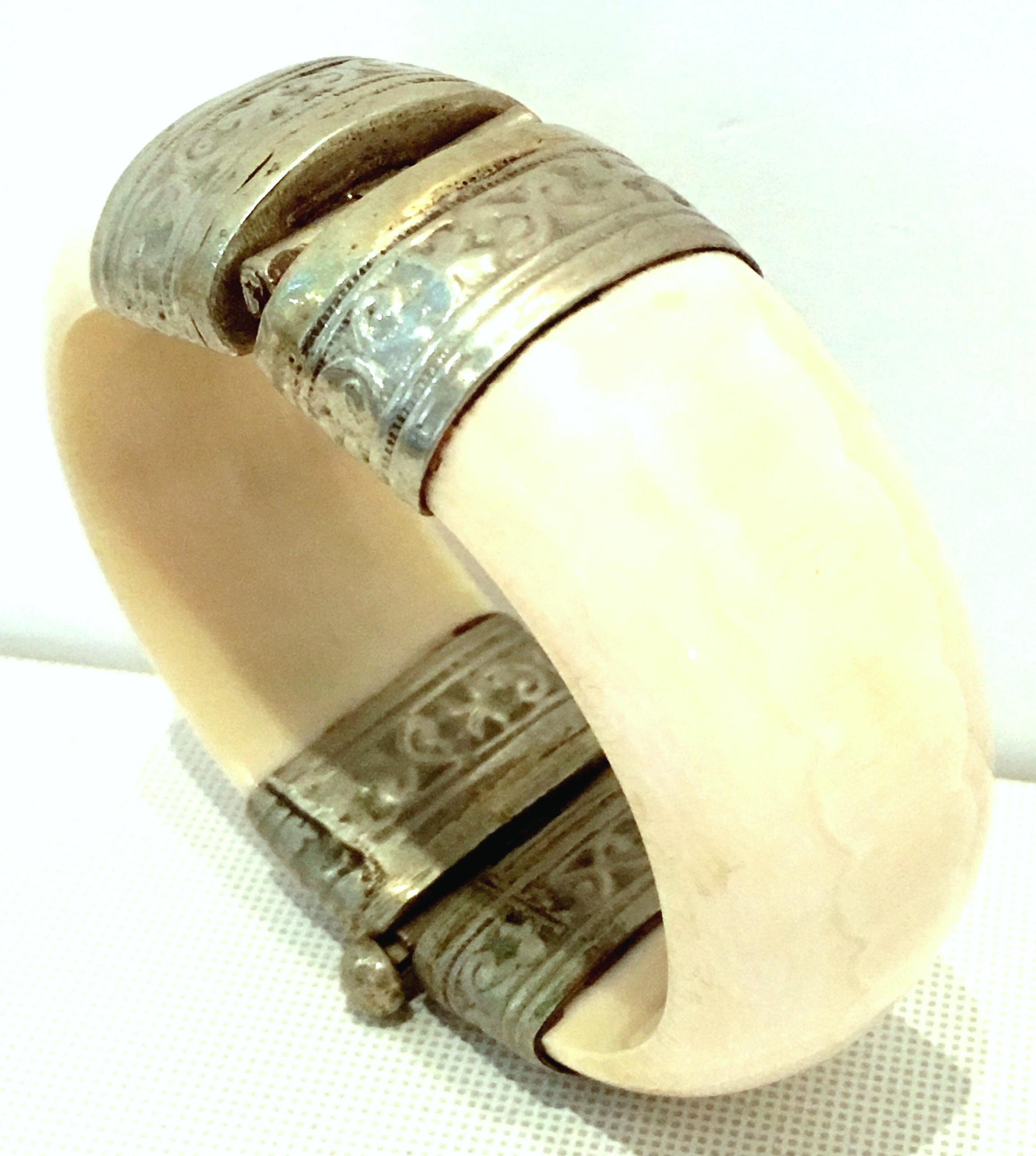 20th Century Bone & Silver Plate Hinge Bangle Bracelet. The bone has a subtle eternity circle pattern. The silver plate caps have a raised abstract arabesque floral style motif. Silver pin closure. Interior dimension approximately, 2.5