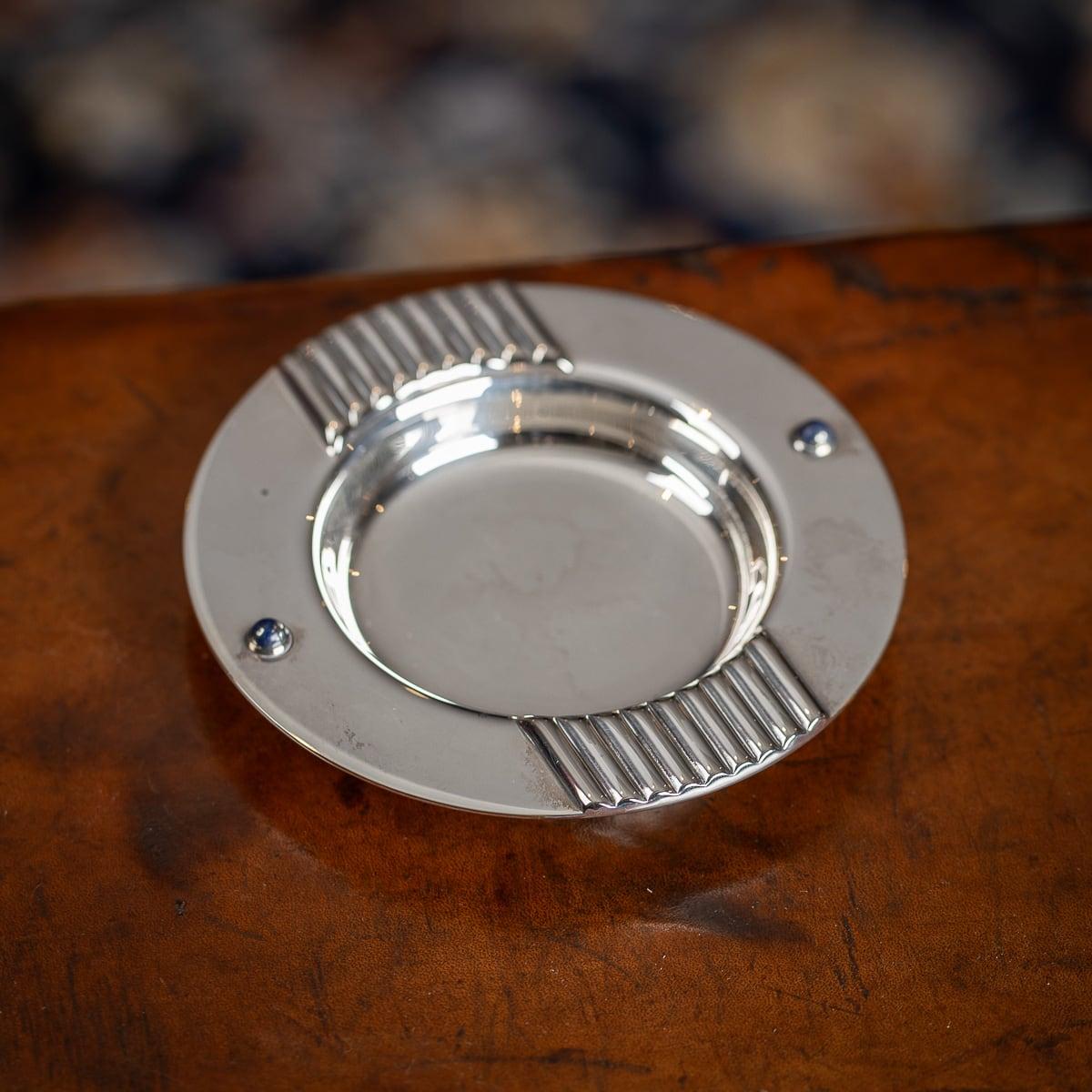 A superb vintage 20th Century silver plate & lapis lazuli ashtray, retailed by Cartier. The ashtray has a ribbed edge for resting a cigarette, along with two lapis cabuchons for added design. Marked on the base 