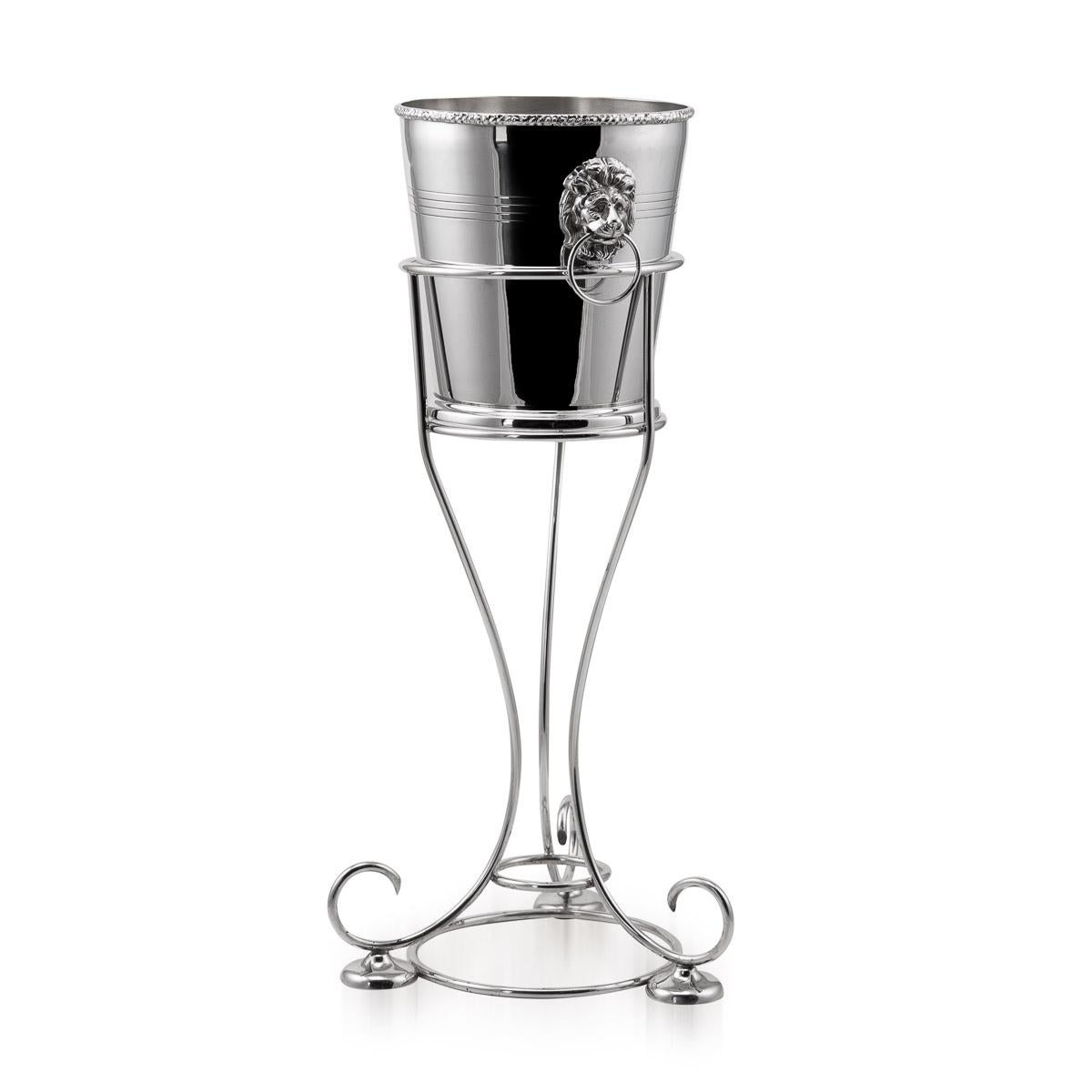 20th Century British silver plated wine cooler with cast lion head handles and scroll stand, made by the renowned silversmiths Mappin & Webb.

Condition
In Great Condition - No Damage, just general wear.

Size
Overall Diameter: 30cm
Height: