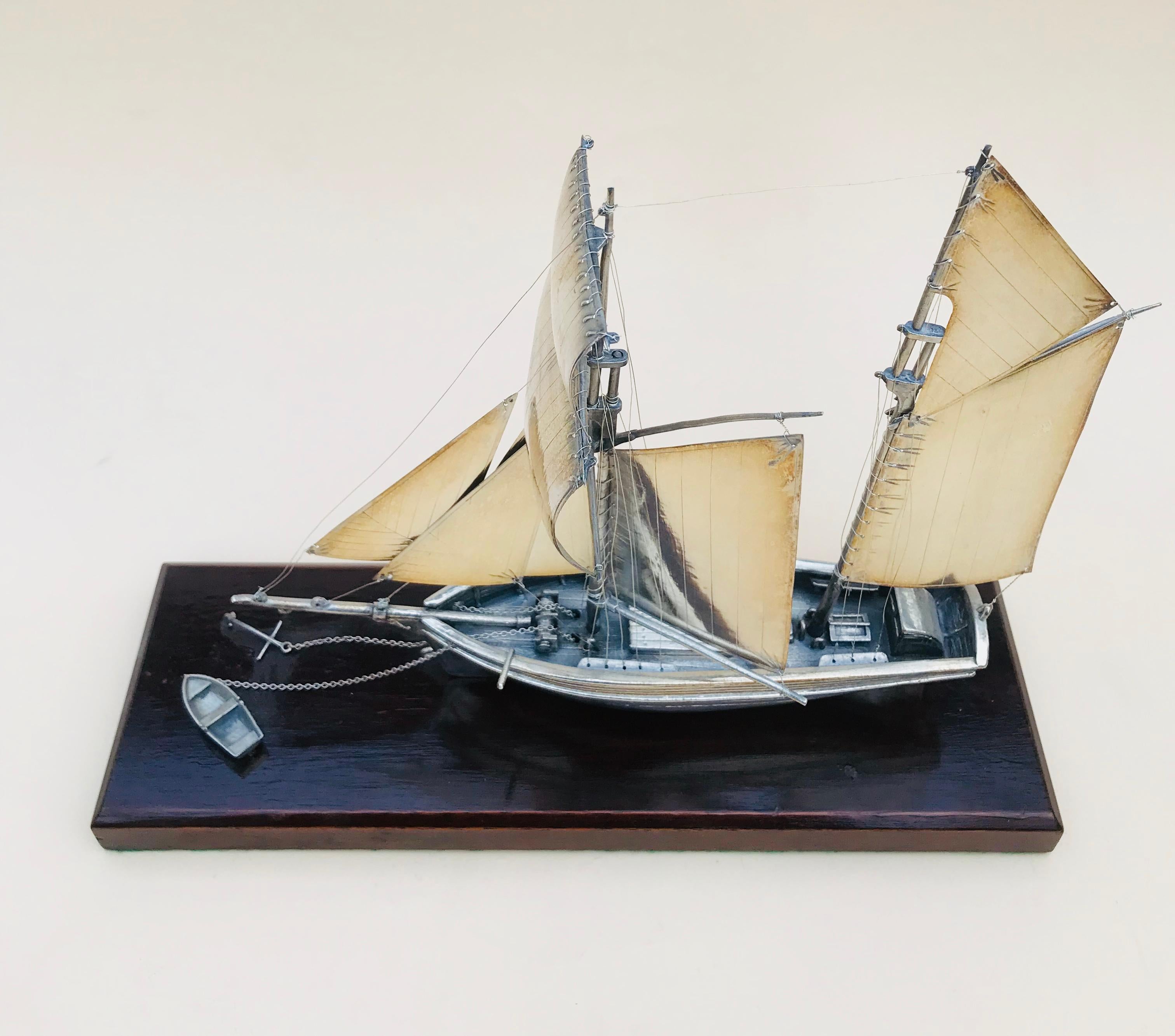 20th century silver twin masted yacht, desk ornament 

This is a lovely piece from the latter part of the 20th century, in the finest detail this is a fully articulated twin masted yacht.
The Yacht has eight sails in all, a small tender dinghy