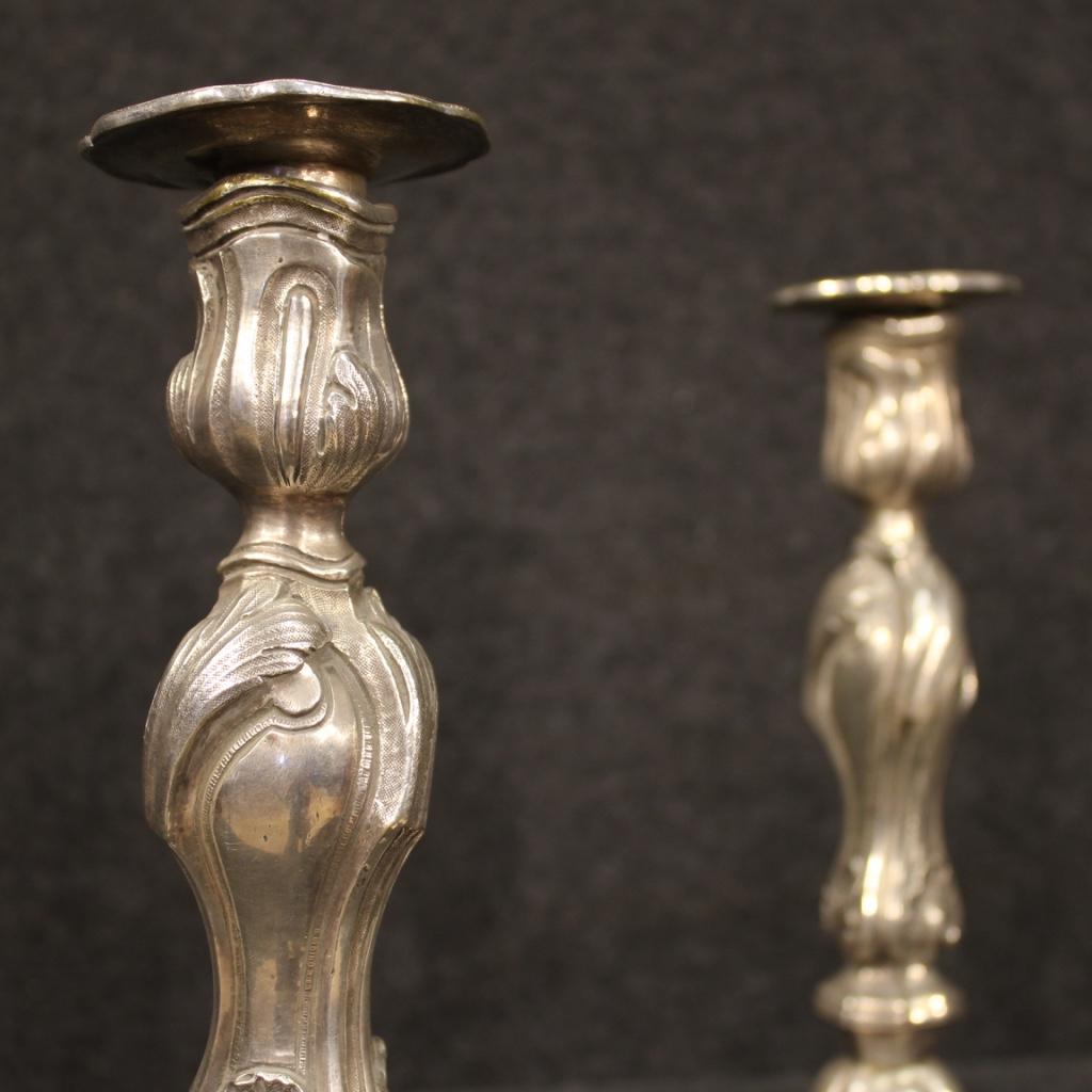 Pair of Italian candleholders from the mid-20th century. Finely chiselled objects in silvered metal, beautifully decorated. One-flame candelabra complete with removable metal wax-save saucers. Central body screwed to the base. They present some