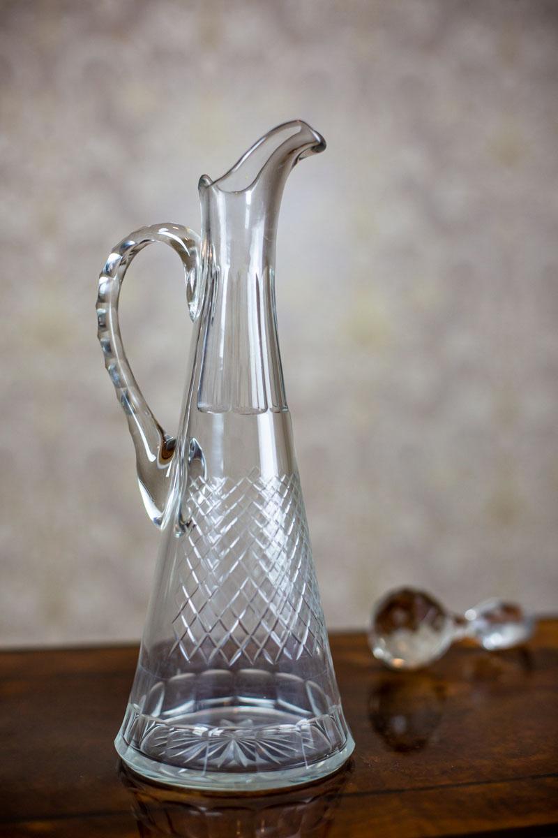 We present you a slender crystal decanter with a handle.

The item is from the early 20th century.

This item is in very good condition and undamaged.