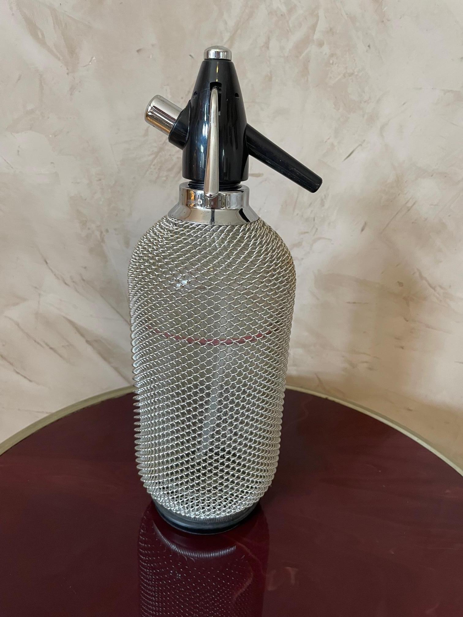 Vintage glass siphon seltzer soda bottle with wire mesh from the 1960s. 
Very good condition. 
Glass bottle stamped at back.