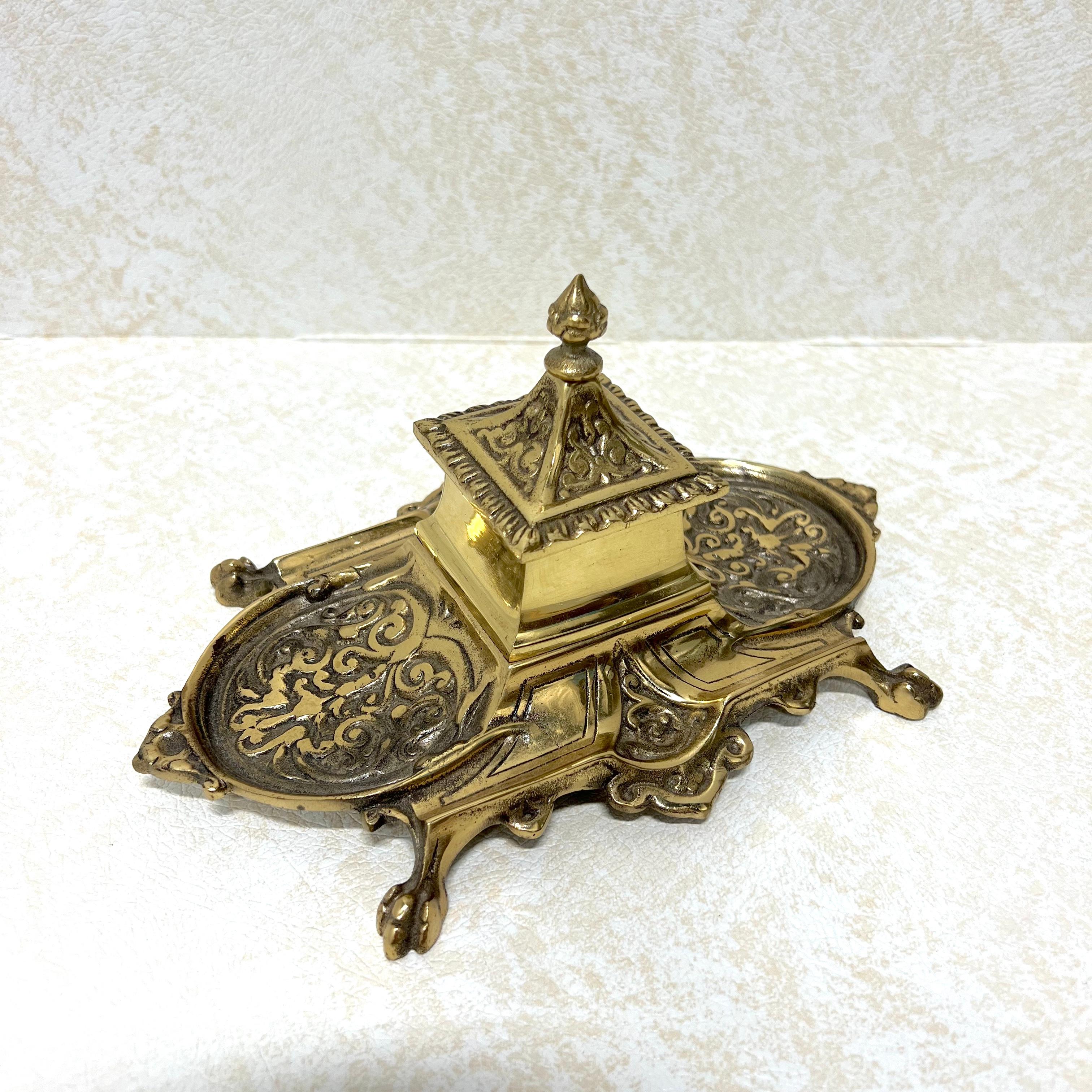 A vintage Asian Japanese decorative desktop inkwell, unbranded. Solid brass in the shape of a pagoda, center inkwell with a hinged lid, flanked on each side by pen rest trays, and raised on ball in claw feet. Made in Japan, in the 20th Century.