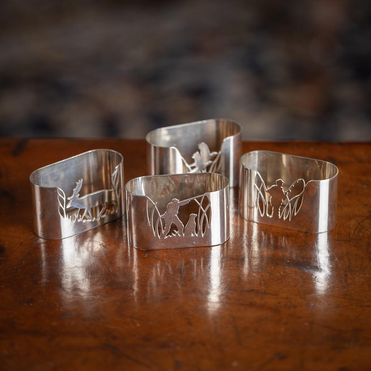 20e siècle : superbe ensemble de quatre porte-serviettes en argent massif. Chaque porte-serviette est percé d'un motif représentant un chasseur et un cerf, un pêcheur et du gibier à plumes. L'ensemble est livré dans un coffret original. Chaque