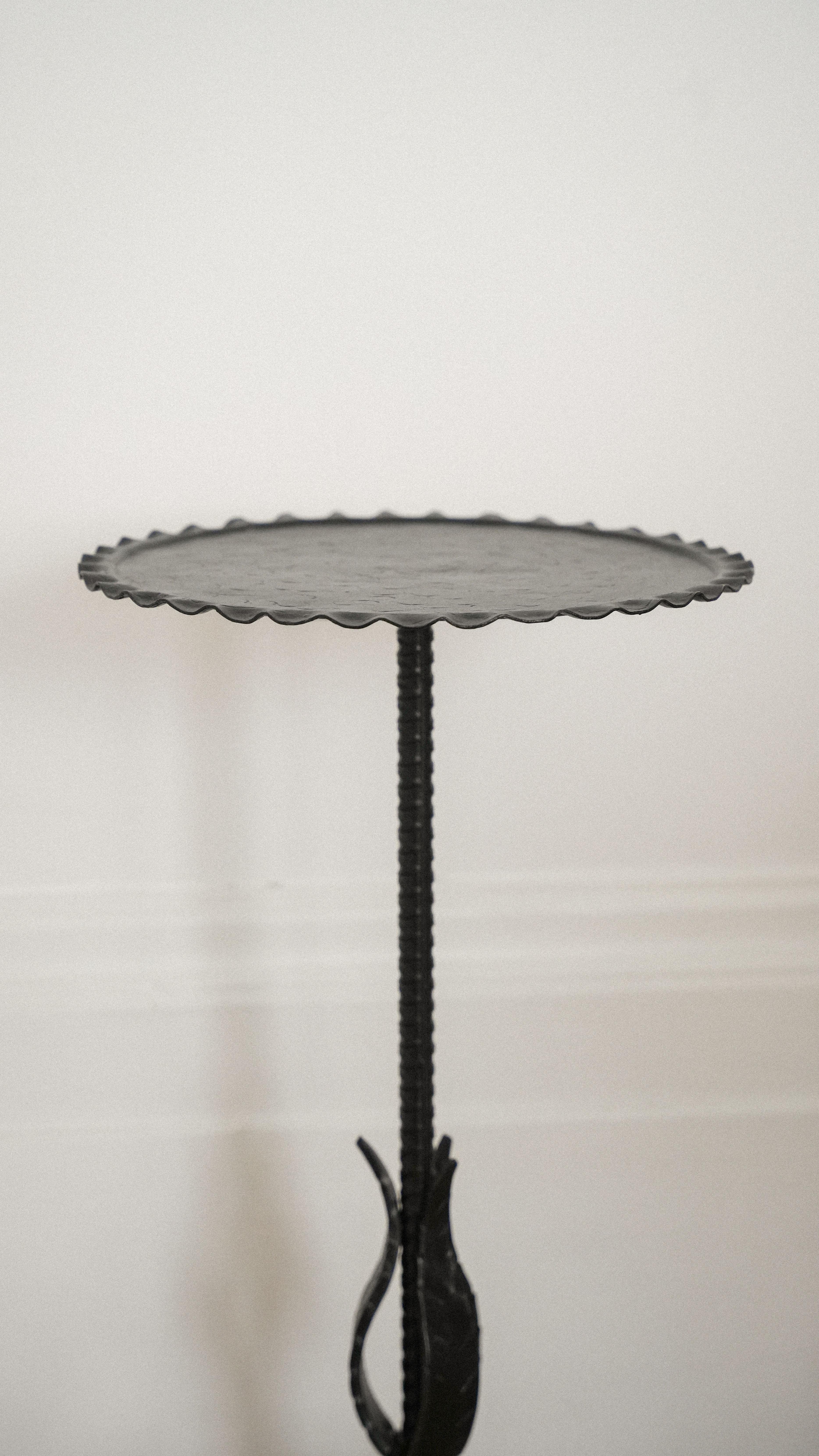 An attractive iron martini table with acanthus leaf detail on the stem, a lightly scalloped top and etching
to the surface. 

The top is rimmed with a ‘piecrust’ edge, and there is a gentle wave etching to the surface. The original gilt surface had