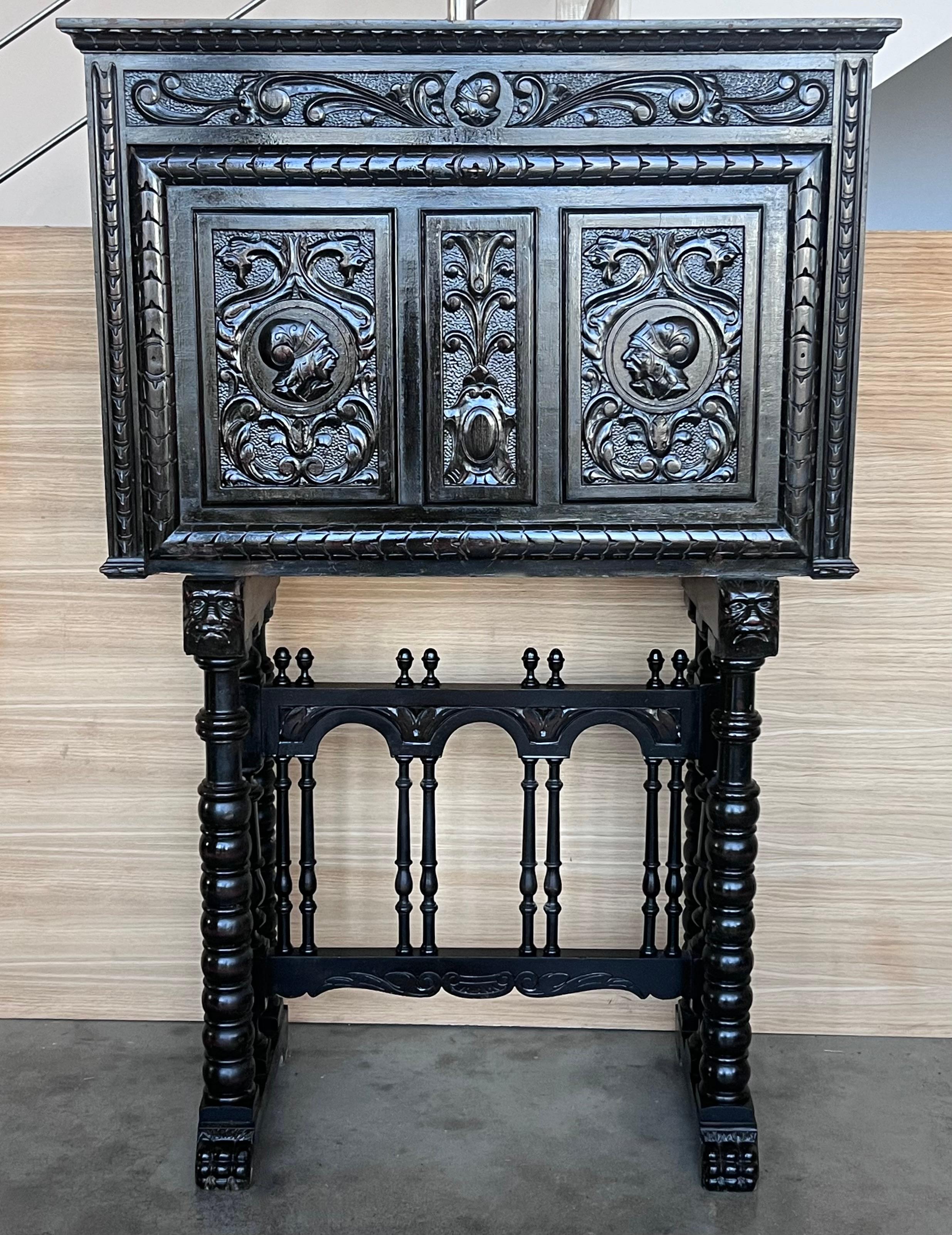 Este Bargueno está adornado con una talla de Don Quijote de la Mancha bordeada de ramas de hojas. El escritorio se apoya en un pedestal unido por un puente de columnas torneadas. Las patas delanteras contienen una talla de dos cabezas de dioses del