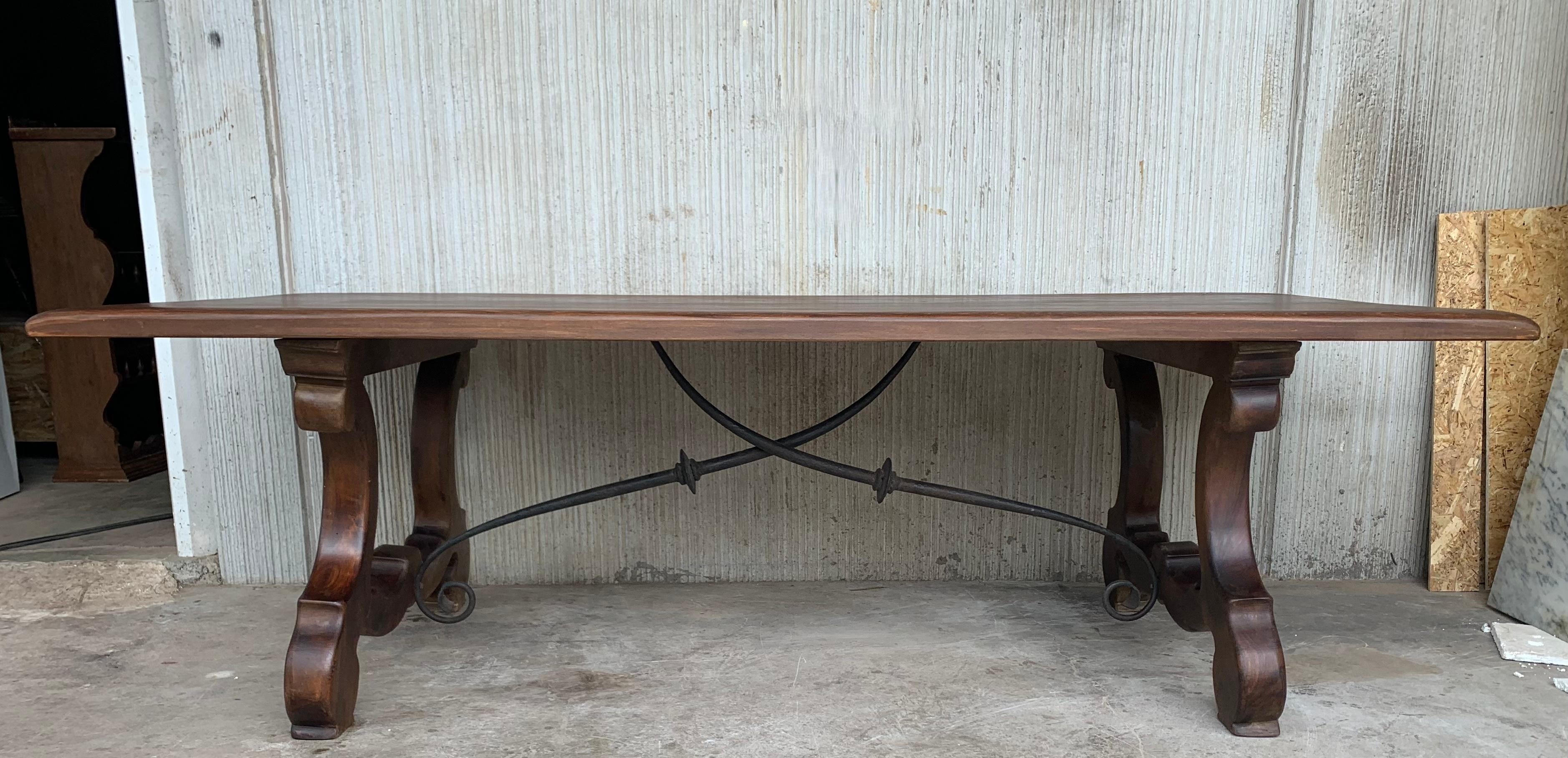 A monumental 20th century Spanish trestle table, having a rectangular framed solid walnut inset board top, resting on hand carved, classical lyre legs joined by four beautifully iron stretchers.

This table was designed for a grand room and seats
