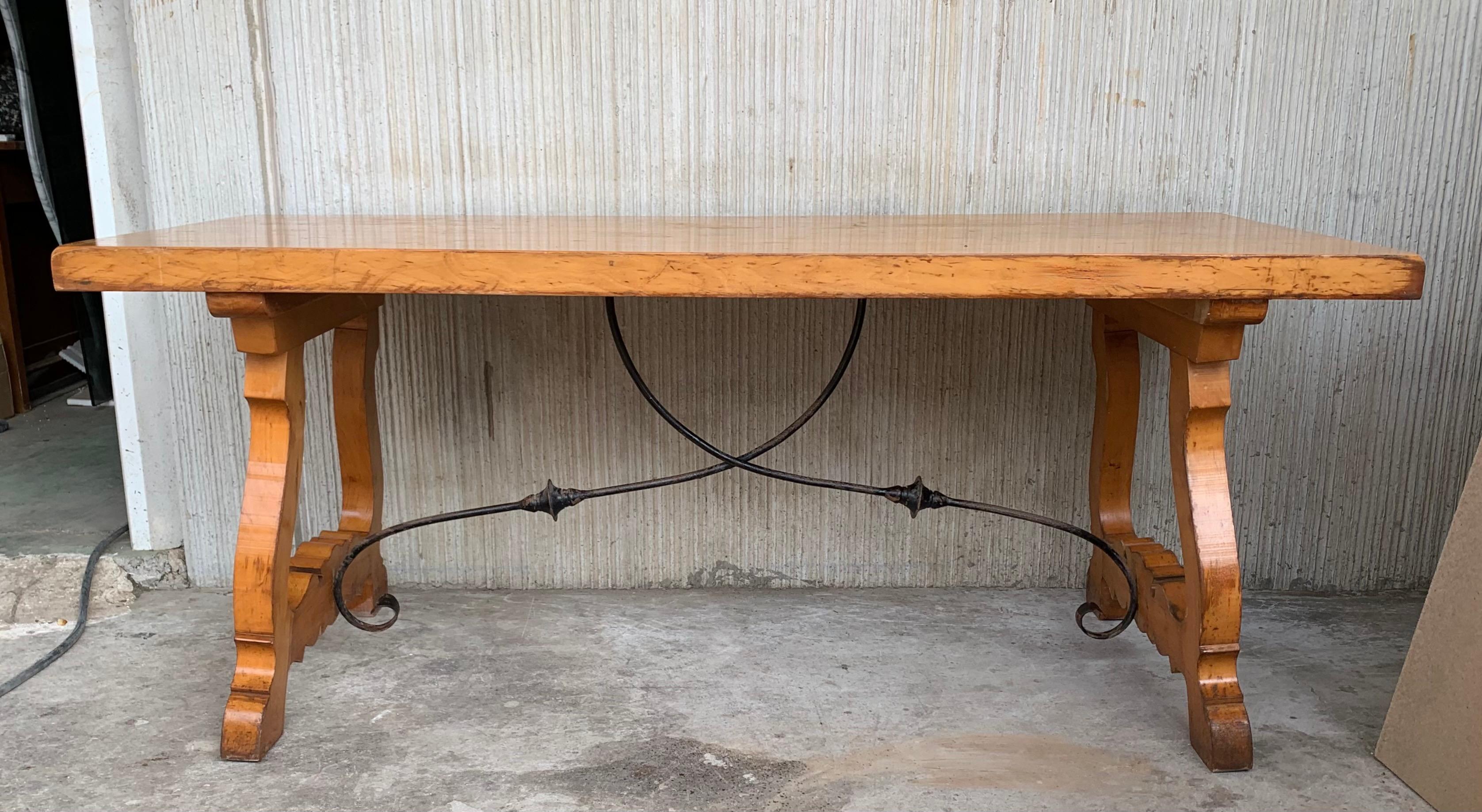 A monumental 20th century Spanish trestle table, having a rectangular framed solid walnut inset board top, resting on hand carved, classical lyre legs joined by four beautifully iron stretchers.

This table was designed for a grand room and seats