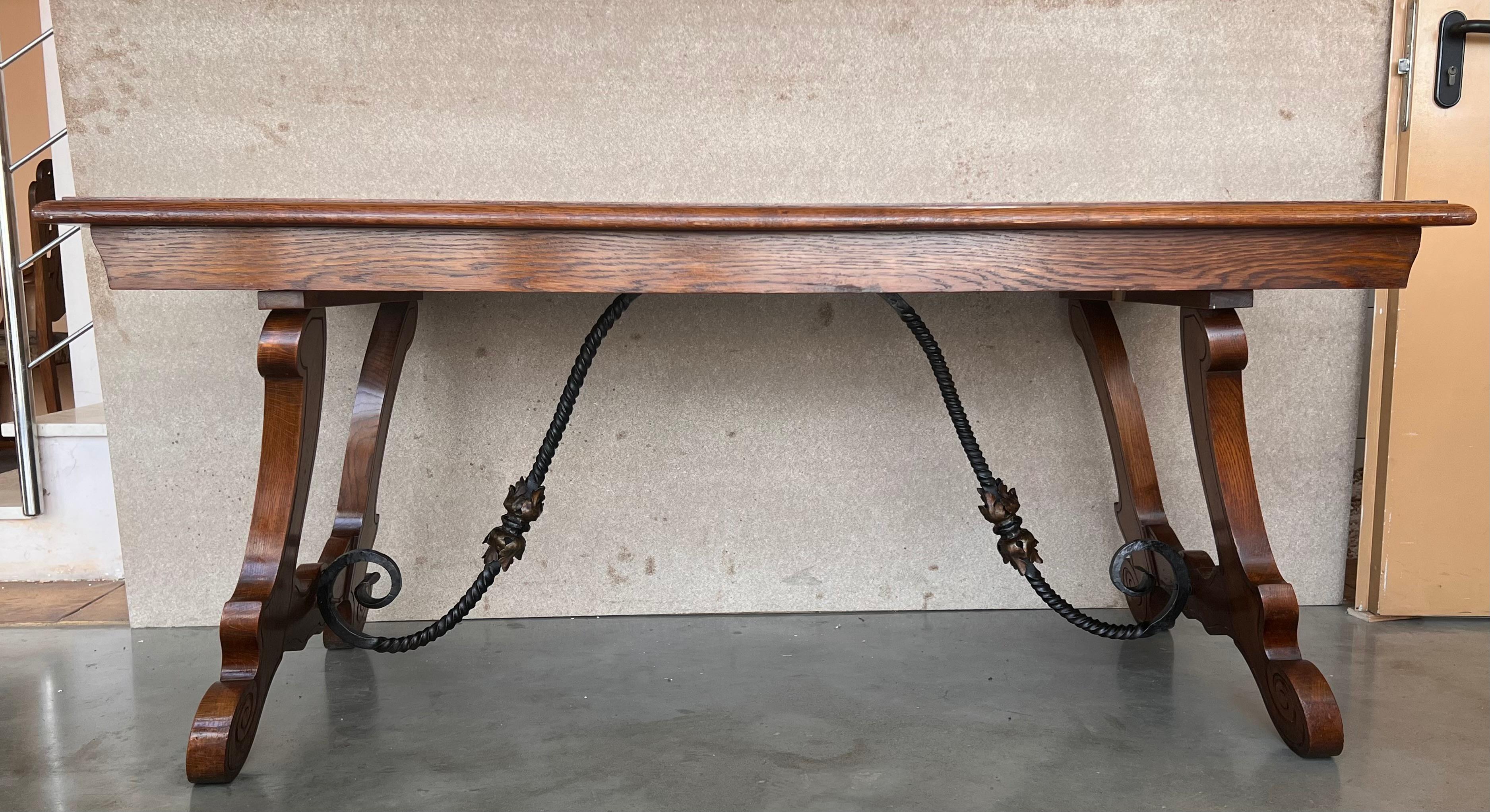 A monumental 20th century Spanish trestle table, having a rectangular framed solid walnut board top, resting on hand carved, classical lyre legs joined by beautifully iron stretchers.

This table was designed for a grand room and seats 6 very