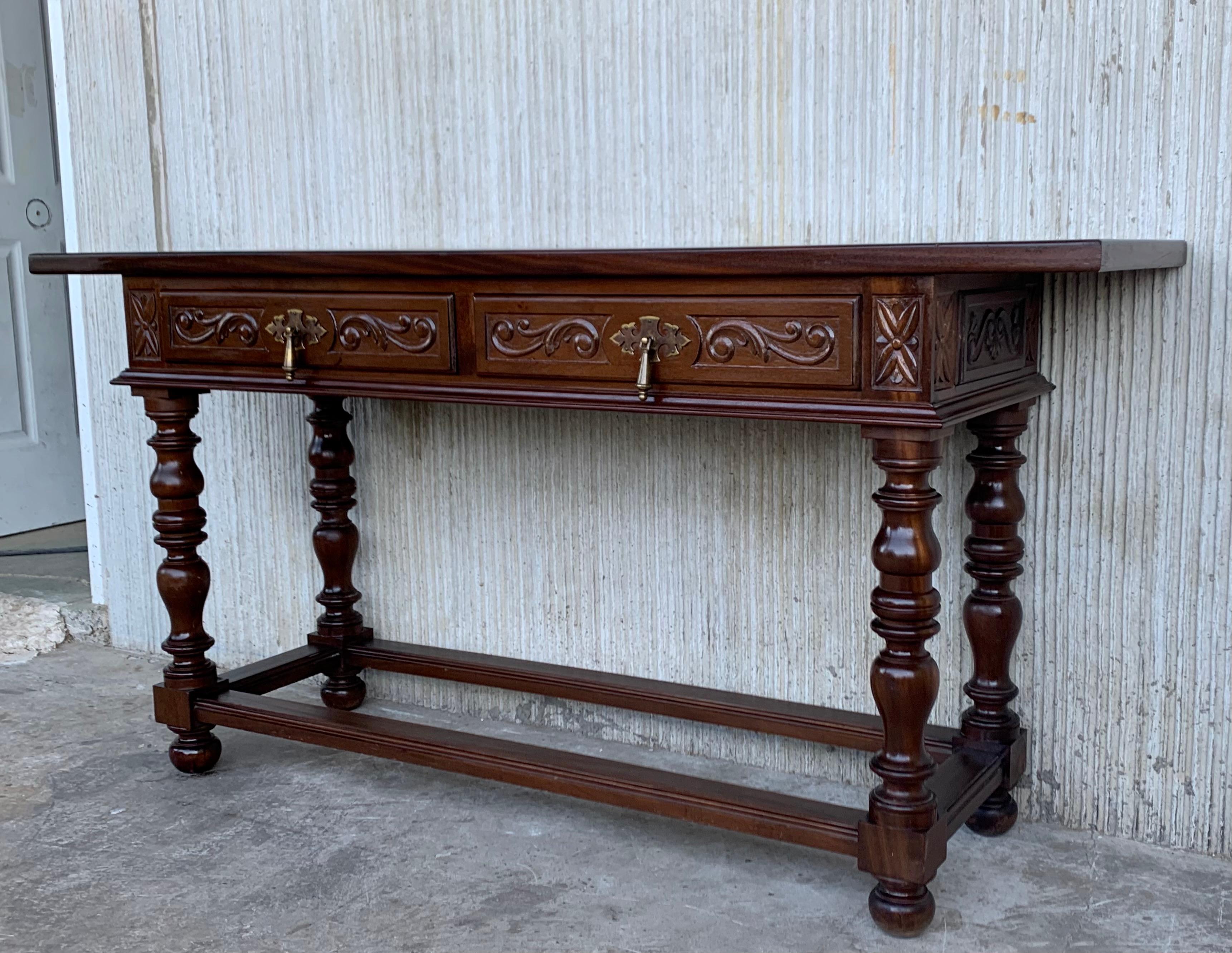 20th Century Spanish Tuscan console table with two drawers and turned legs. It is characteristic of Spanish Baroque furniture with a thick single piece top, simple bold chip carved ornament and bold turnings. It has a rich lustrous patina.

The