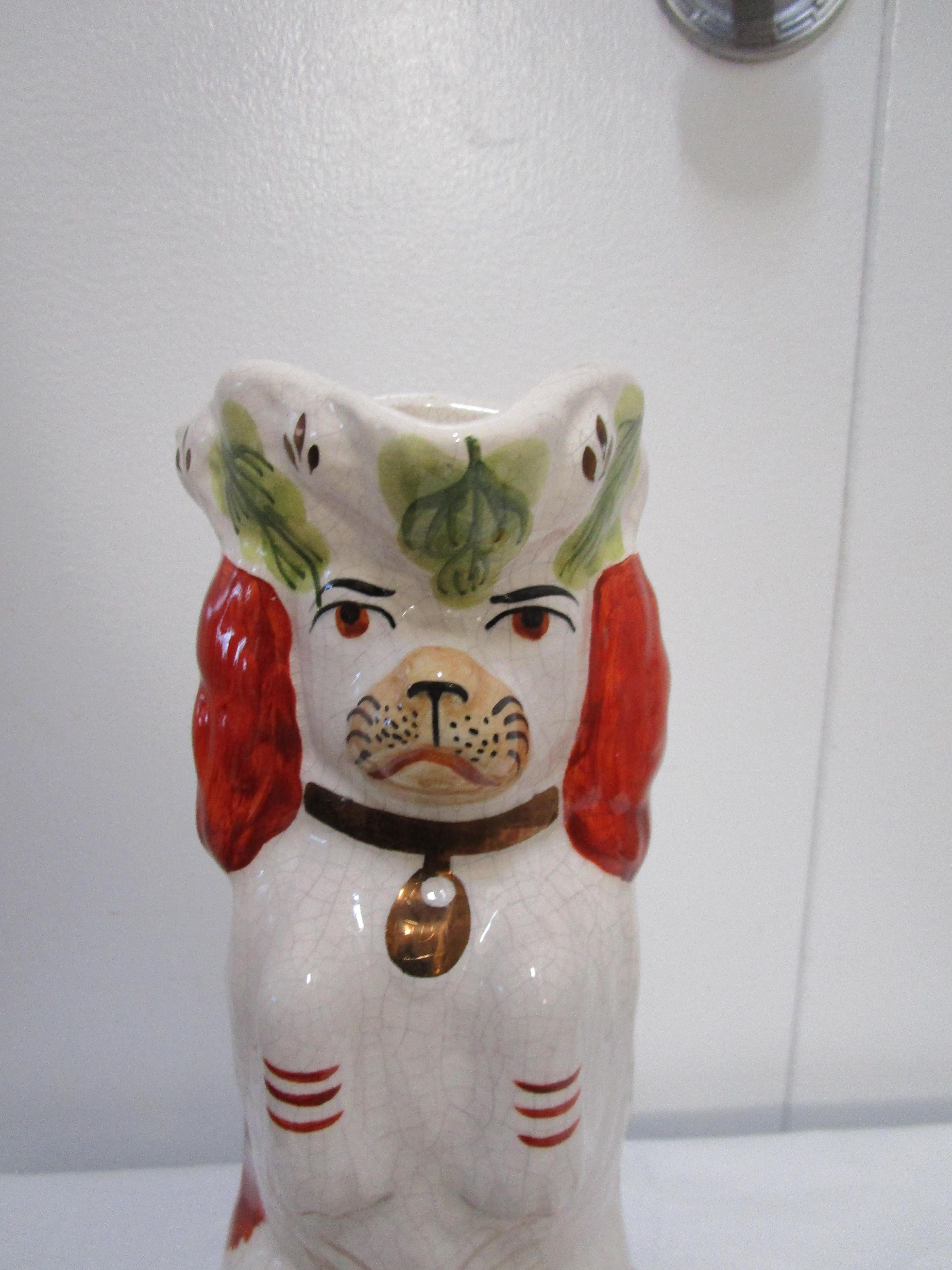 This Staffordshire Spaniel jug is impertinent, from his expression to his hopeful gaze. The eyes seem animated and almost lifelike. This jug is in excellent condition with bright red, white and green and gilt touches in the form of the pup's gold