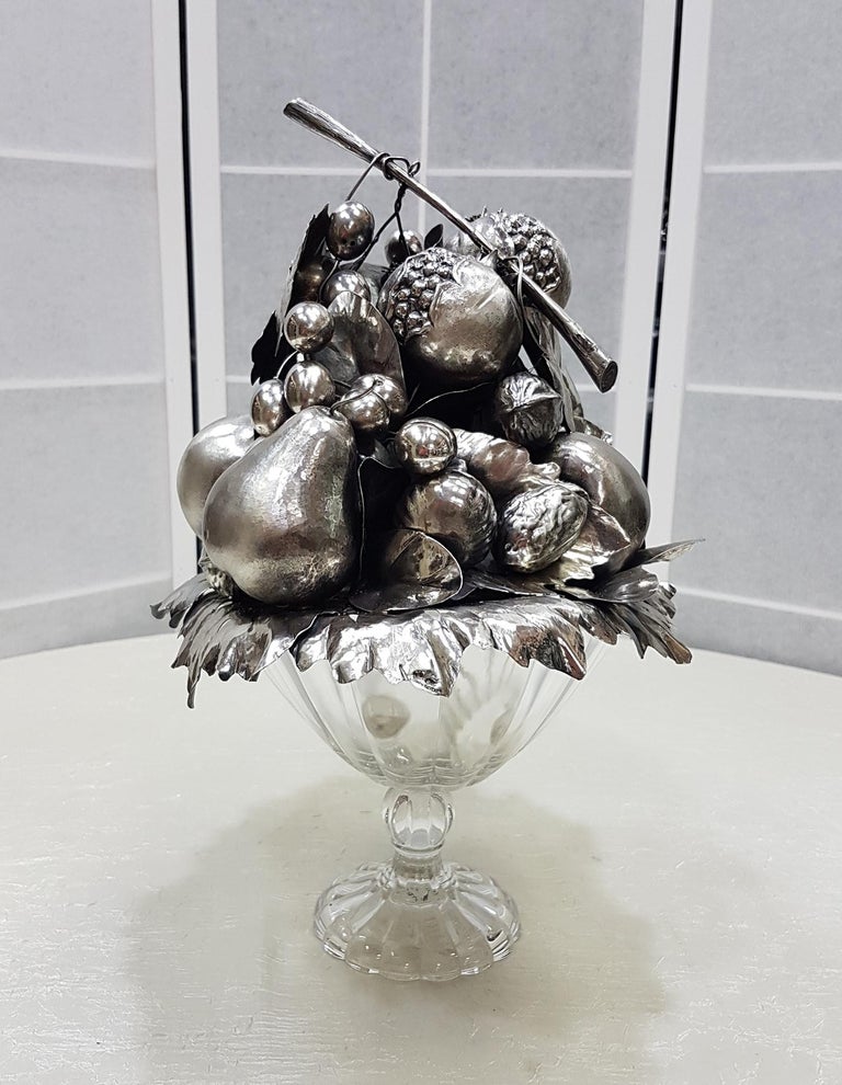 Solid sterling silver centerpiece with fruits and leaves composition made by chiseled silver sheet.
The finish is burnished to highlight the workmanship.
This composition was placed on a crystal base to enhance its brilliance and grandeur.
   