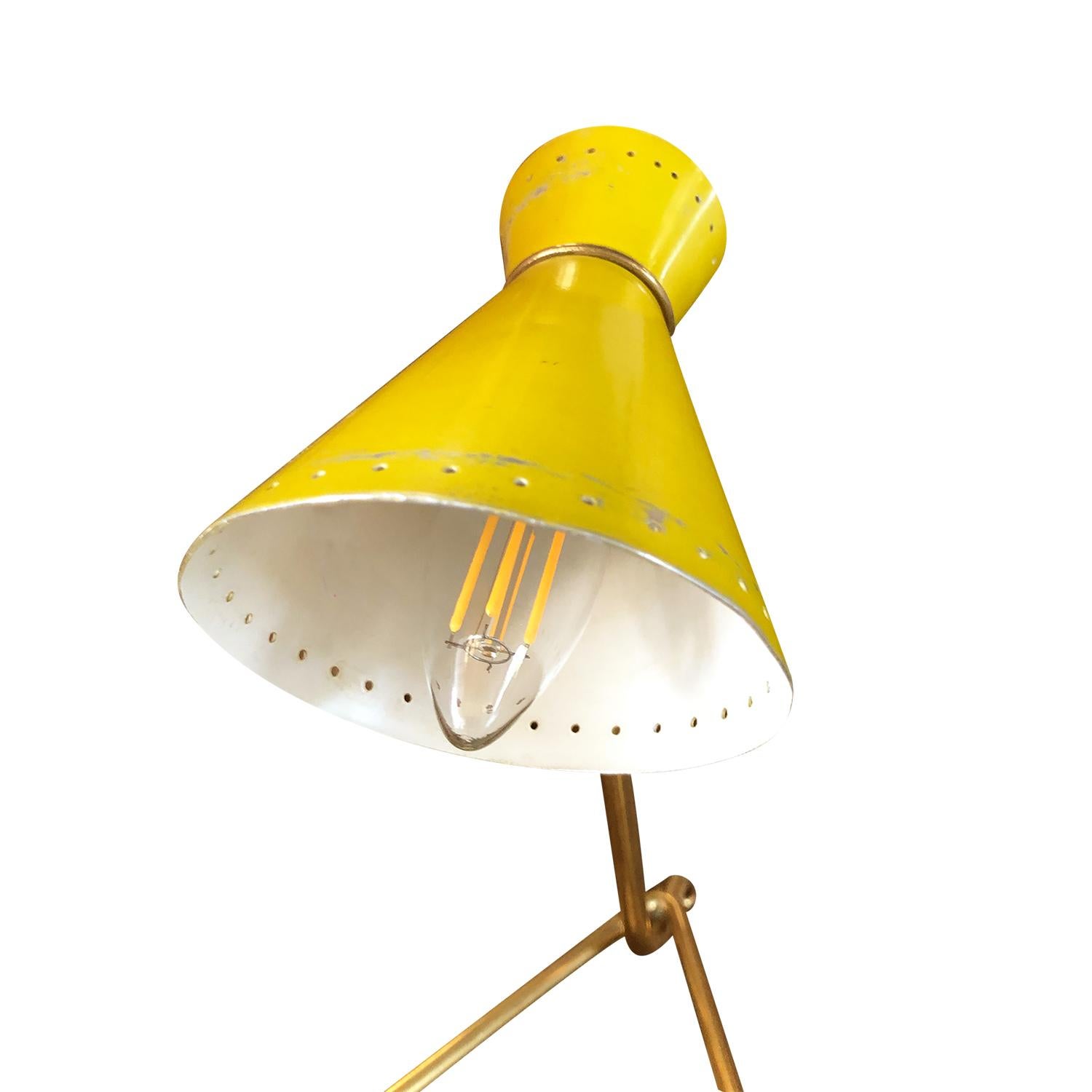A vintage Mid-Century Modern Italian small desk lamp or table lamp made of a brass base and an adjustable yellow lacquered aluminum shade, featuring a one light socket. Produced by Stilnovo in good condition. The wires have been renewed. Wear
