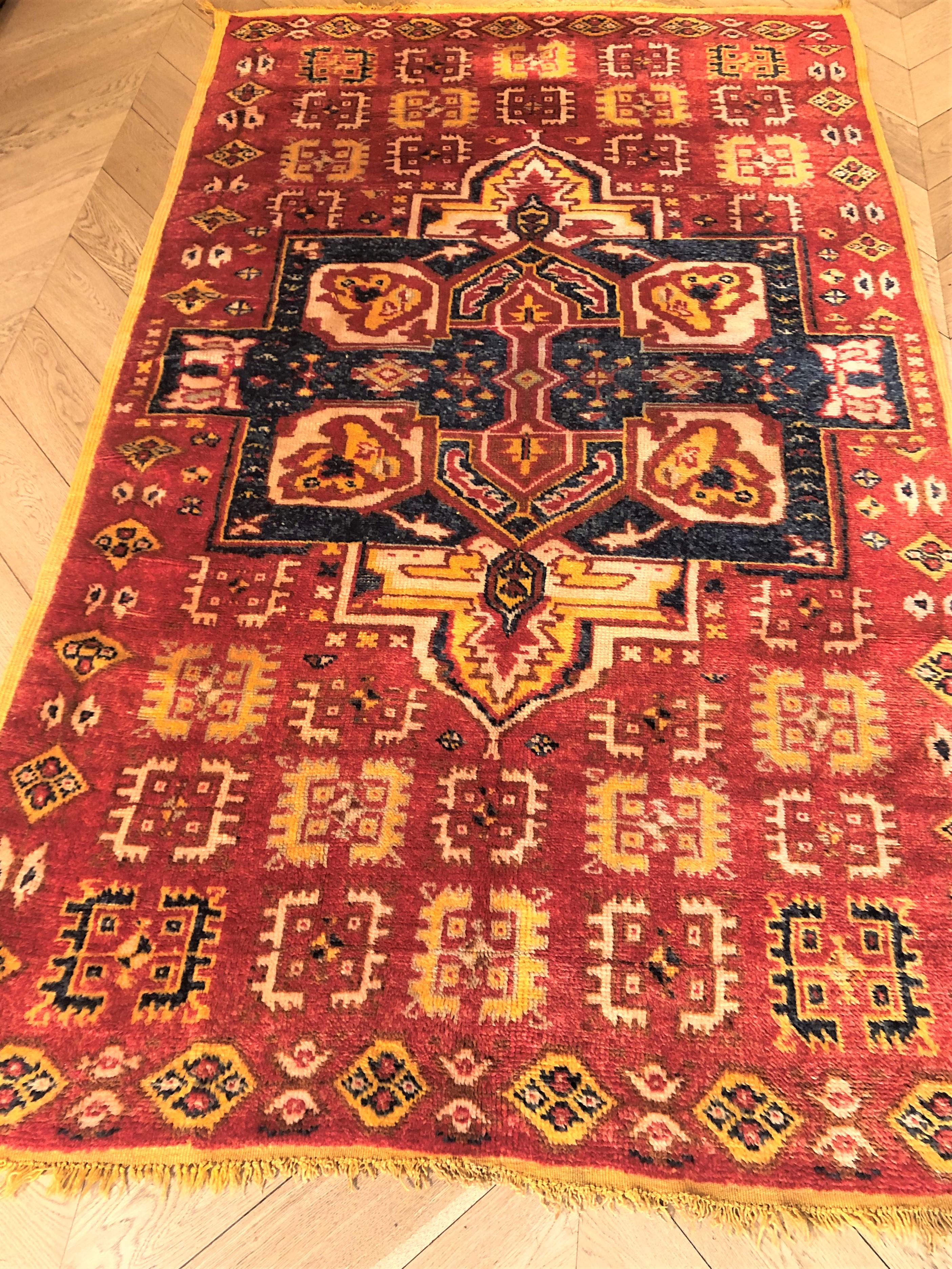 This Berber carpet from the Ouarzadeh region has the characteristic saffron-colored wool structure. The large blue medallion is not common in this typology, more often decorated with repetitive elements.
The combination of warm and bright colors is