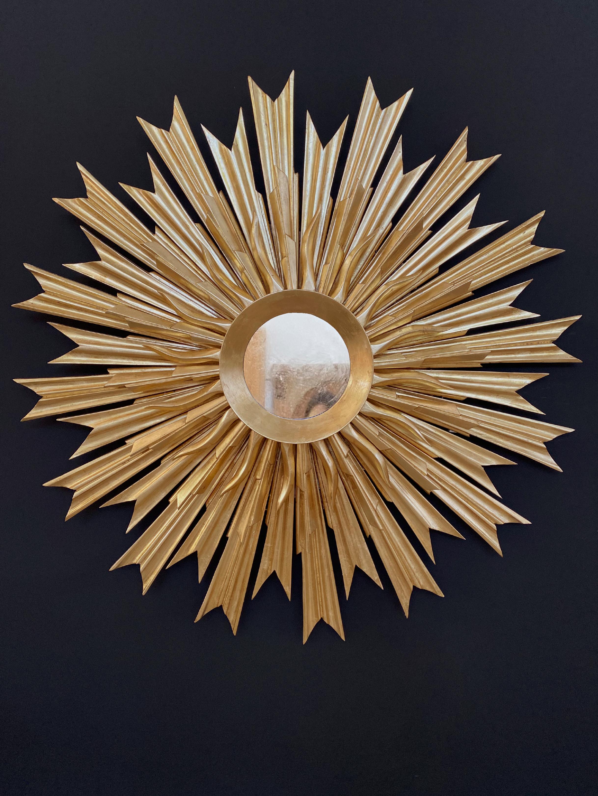 Impresionante espejo sunburst restaurado del siglo pasado, que muestra una elegancia intemporal y una artesanía excepcional. Esta exquisita pieza está totalmente tallada a mano. Presenta una doble hilera de rayos de madera meticulosamente tallados,